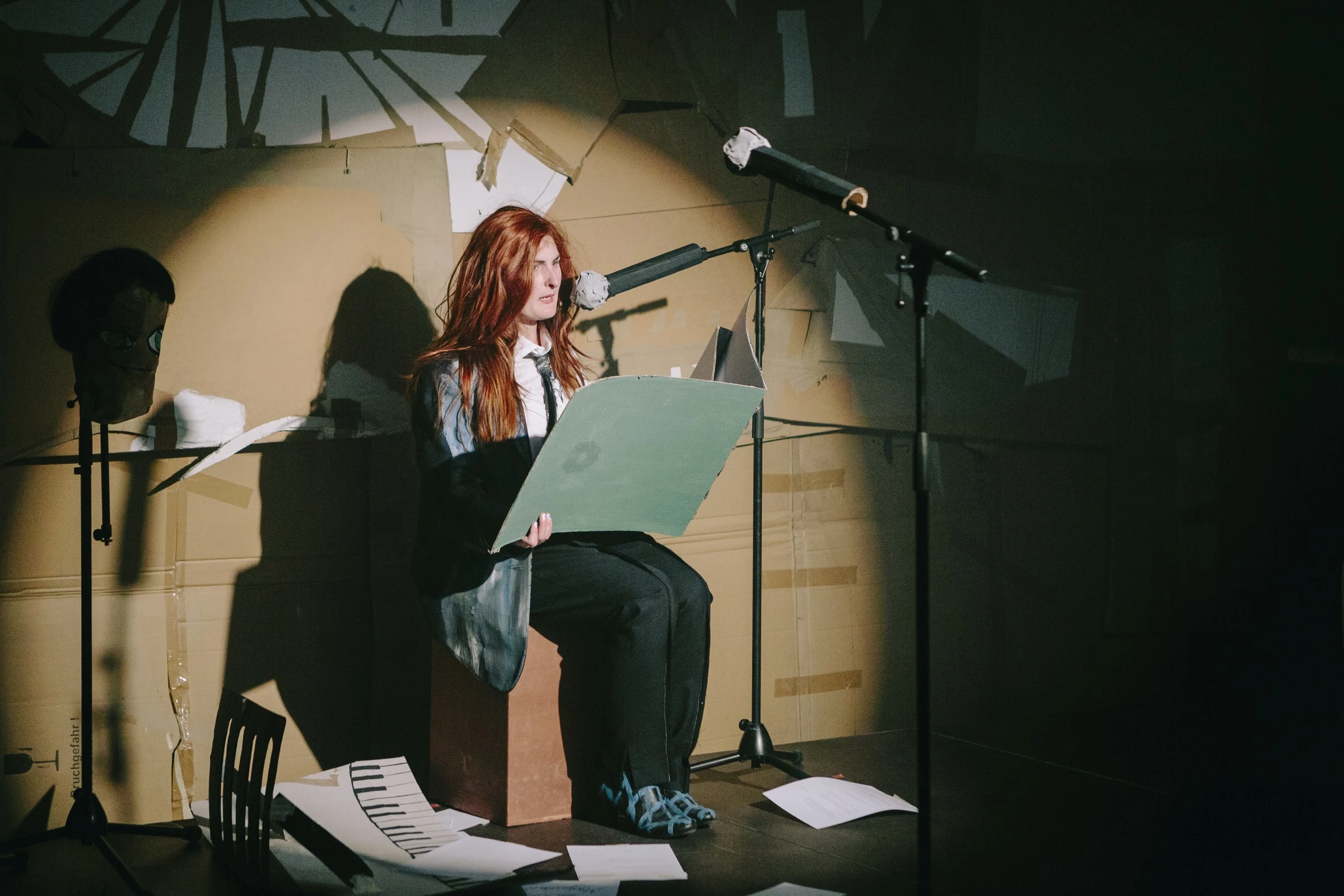 Charlotte Gash seated at a microphone reading a green cardboard diary.