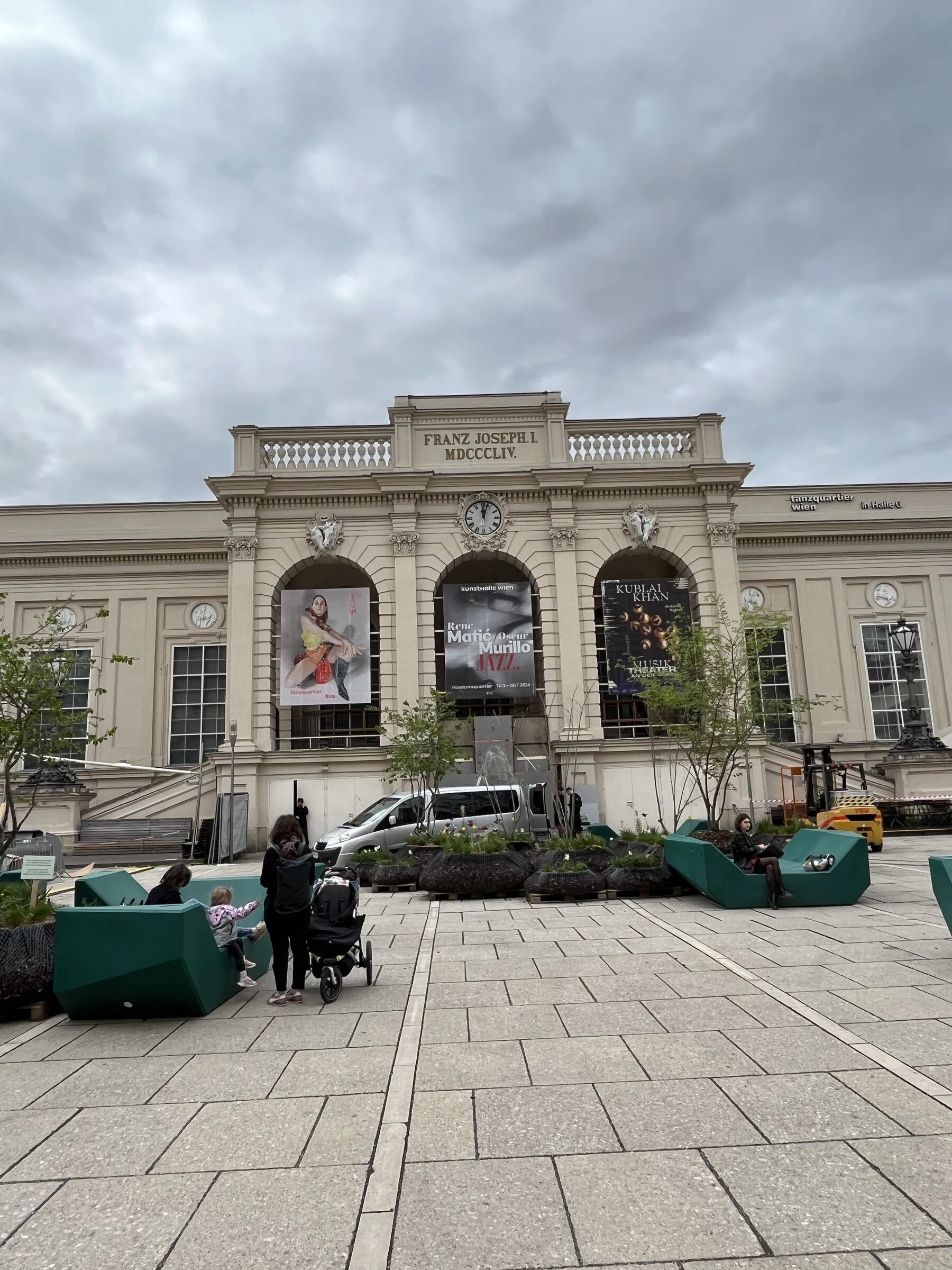 A wide view of the Tanzquartier building and courtyard with the portrait poster on its facade.