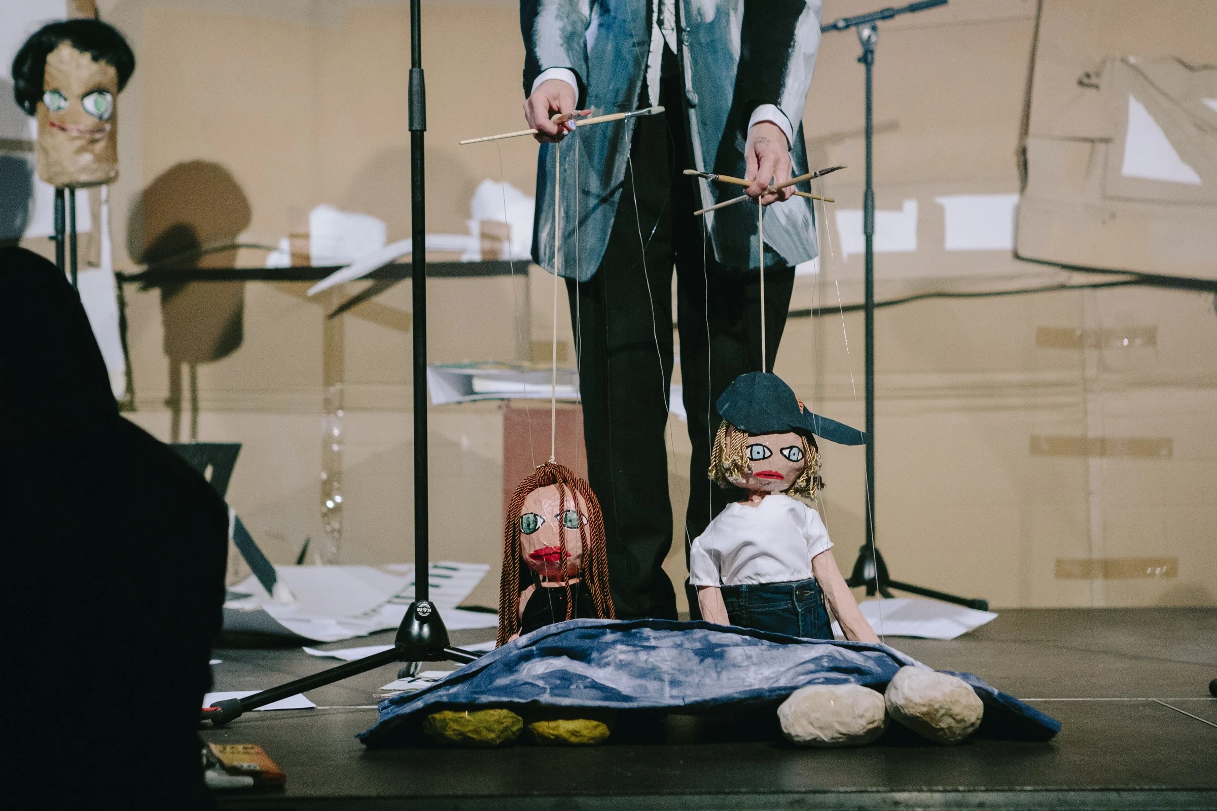Charlotte Gash operating two handmade puppets on the cardboard stage.