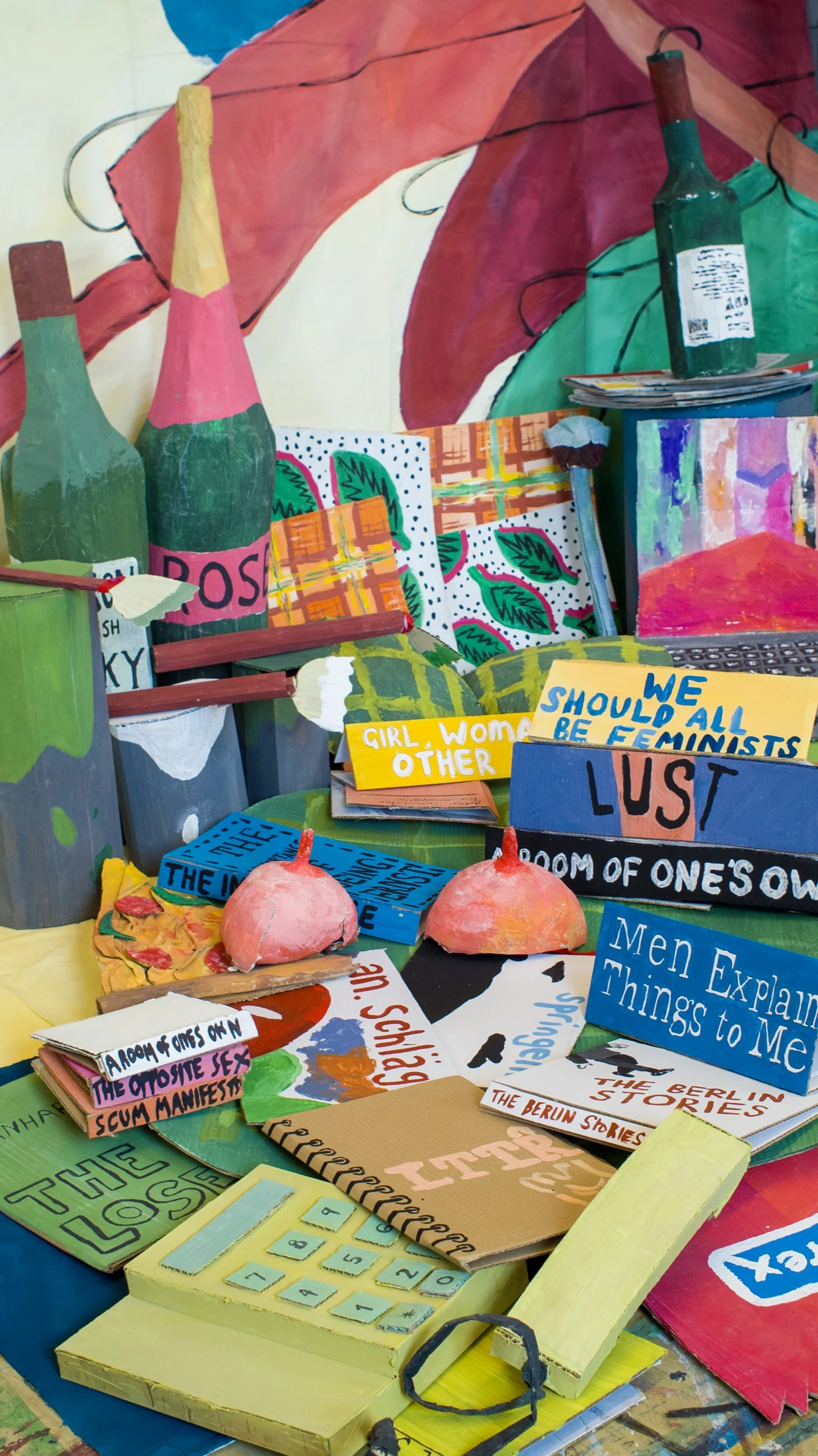 Cardboard books and a yellow telephone arranged beneath painted bottles and a laptop in BEDROOM.