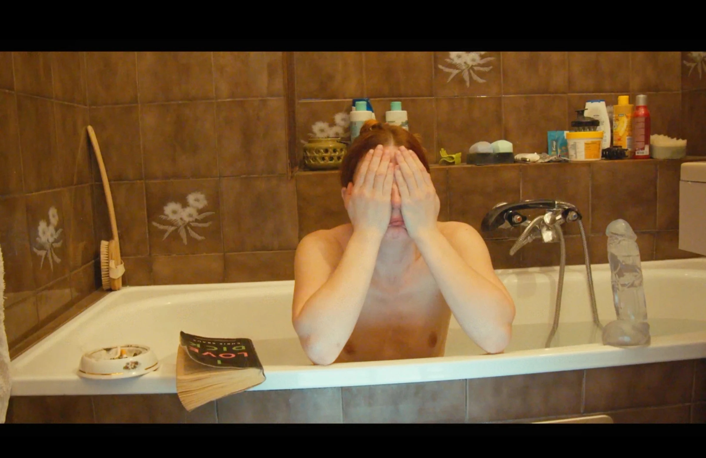 Charlotte sitting in a bathtub with her hands covering her face.