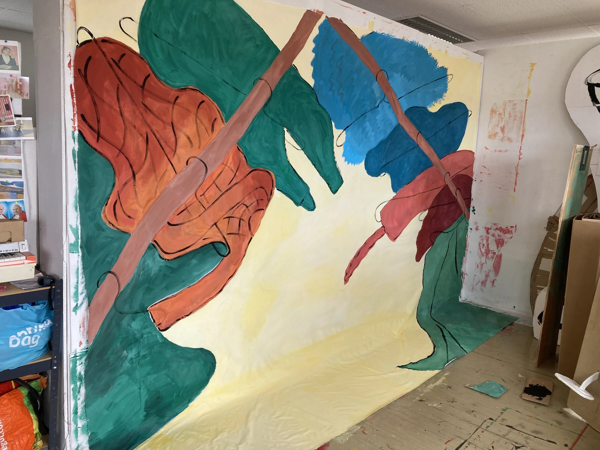 A colourful painted backdrop with oversized green, orange and blue leaves in the studio.