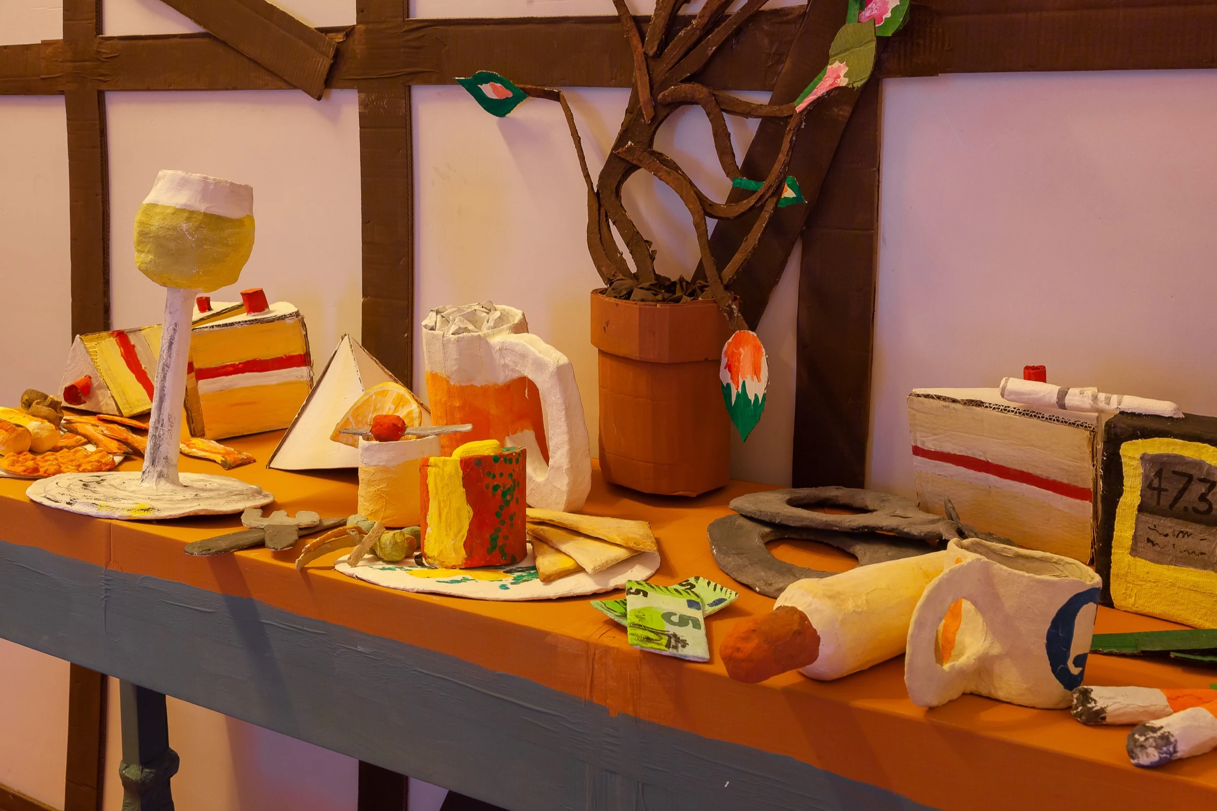 Handmade cardboard food, packaging and a plant arranged on the kitchen counter.