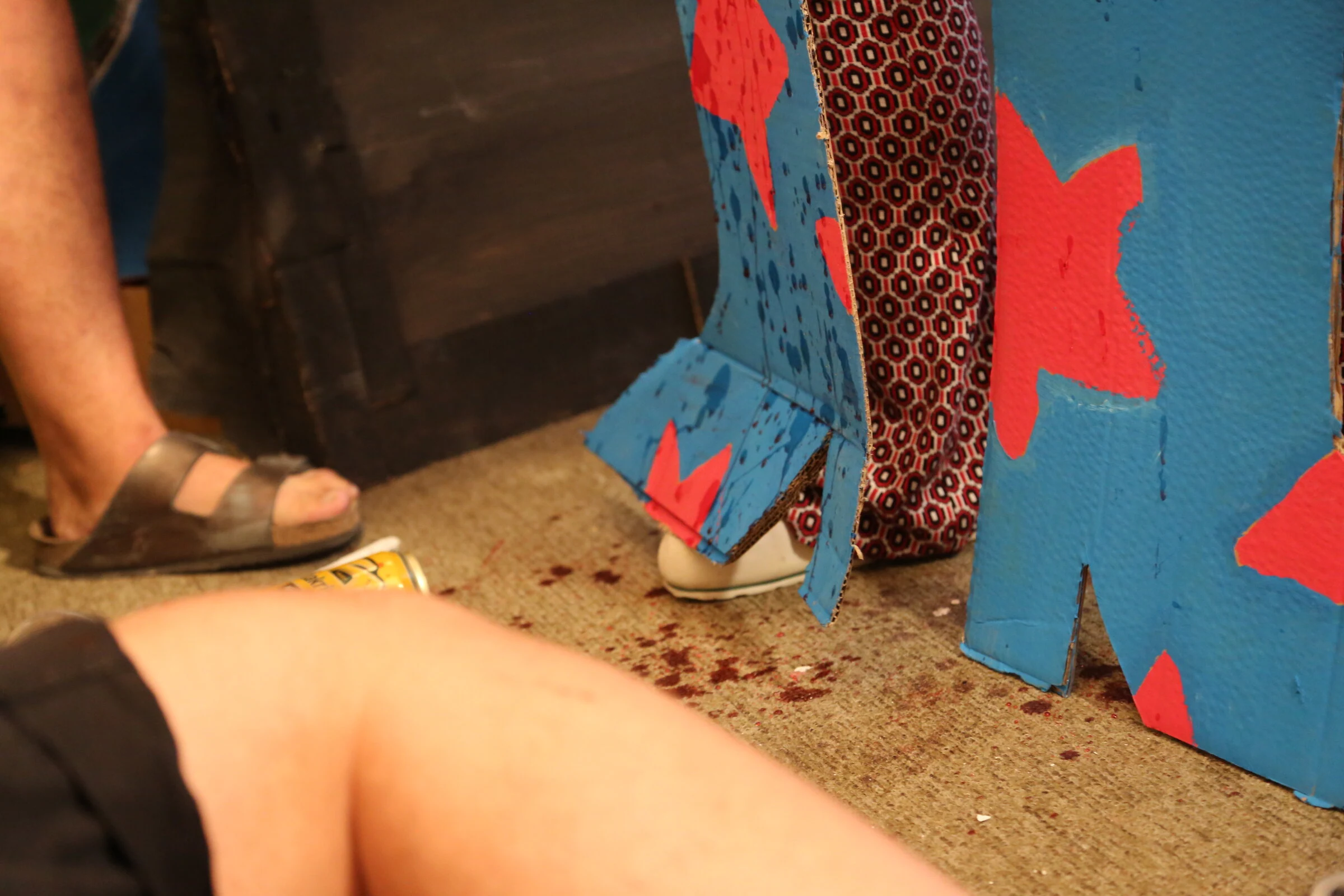 Blue cardboard boots decorated with red stars among the performers and audience.