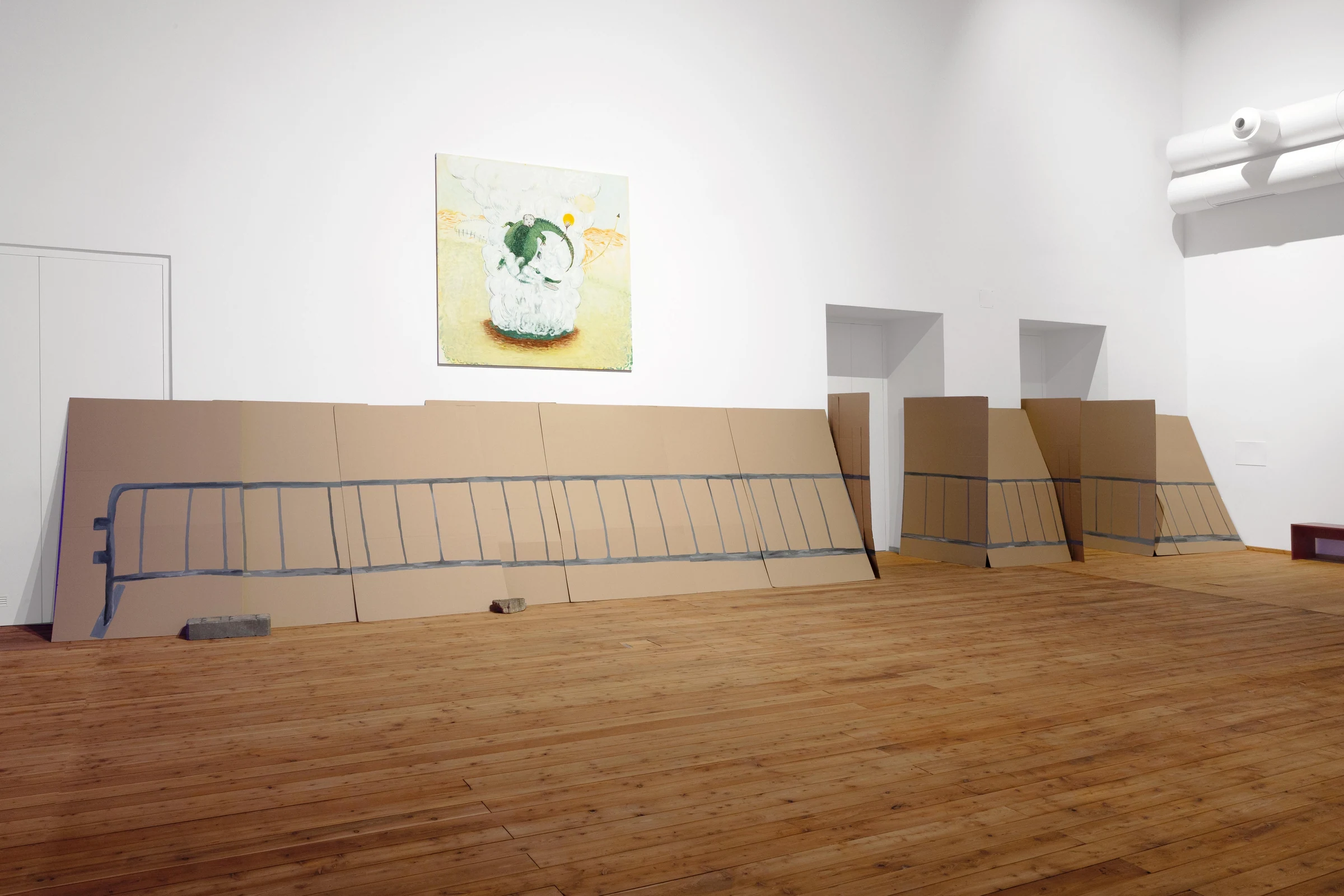 A wide view of cardboard fence panels arranged along the gallery walls and doorways.