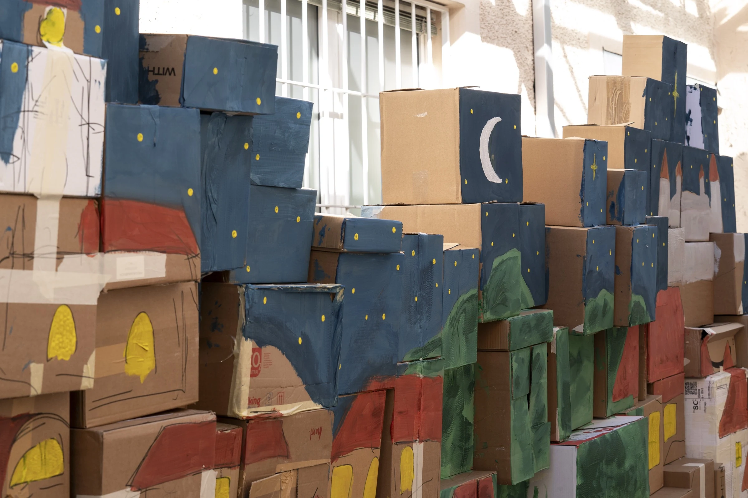 Painted cardboard scenery with houses, mountains, stars and a crescent moon.