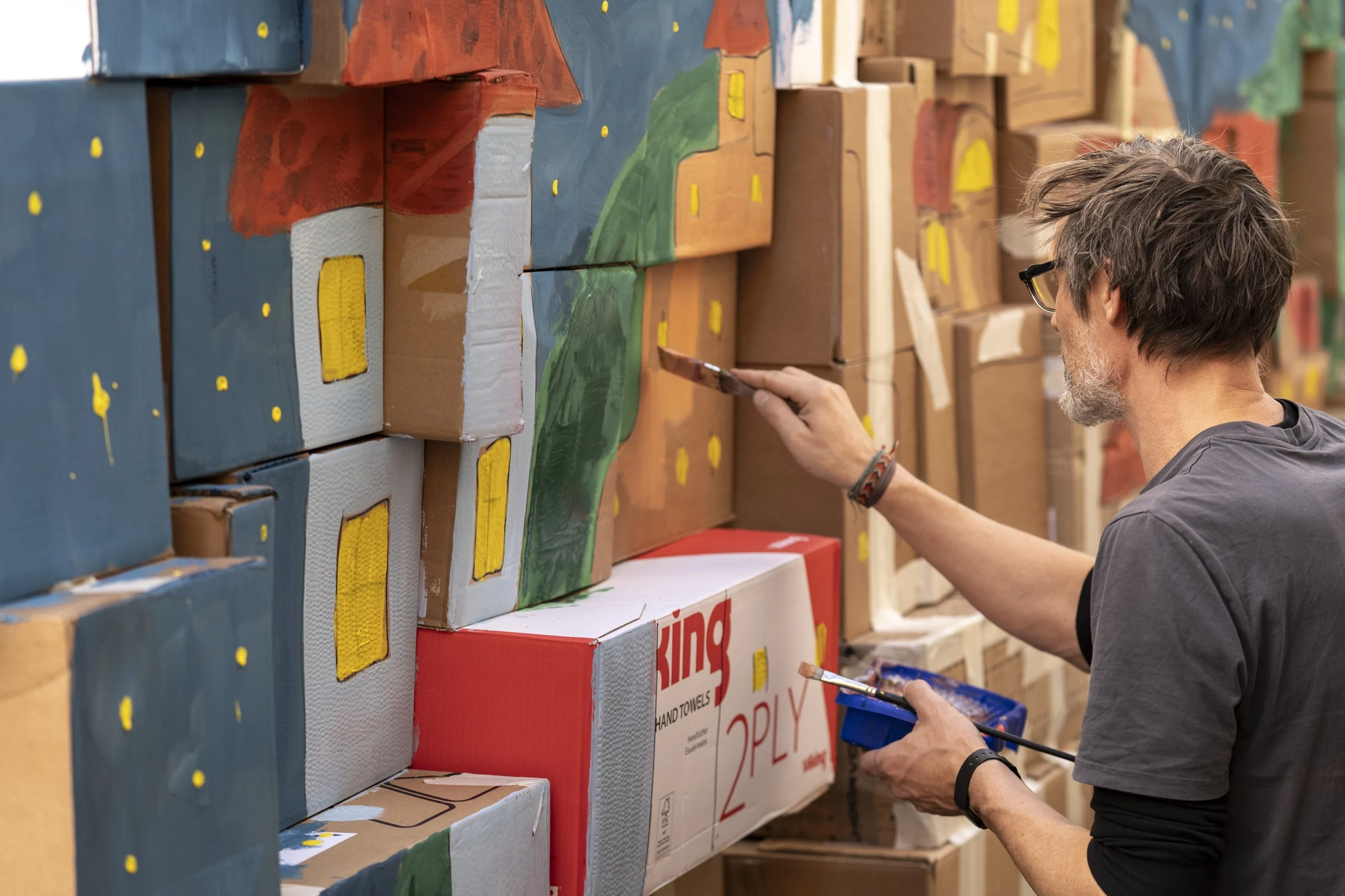 A participant painting a castle onto cardboard boxes.