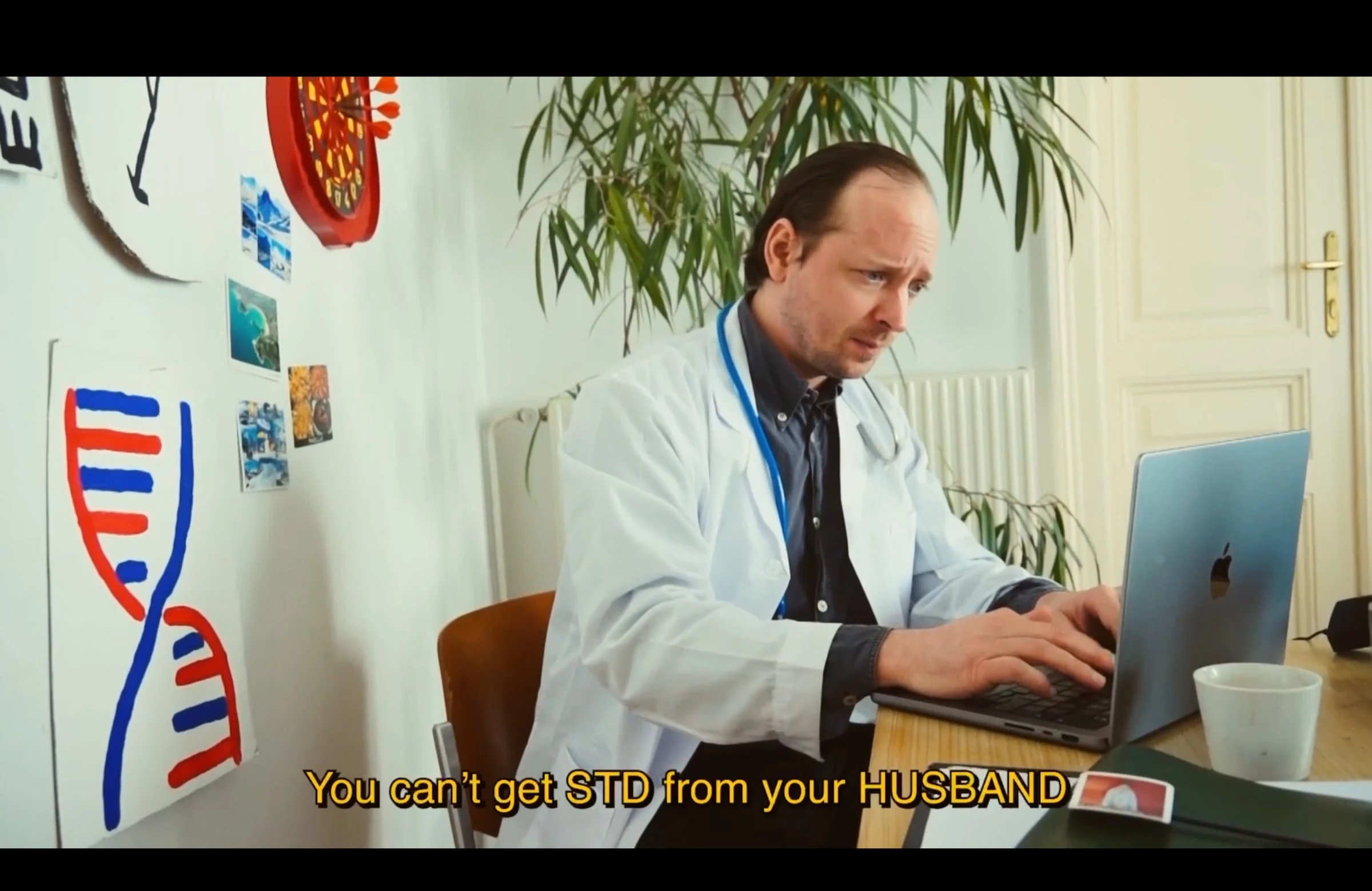 A character playing a doctor, wearing a white coat and stethoscope while using a laptop.