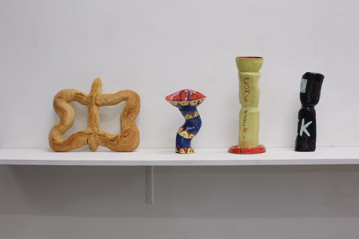 Four ceramic sculptures and vessels displayed on a white wall shelf.
