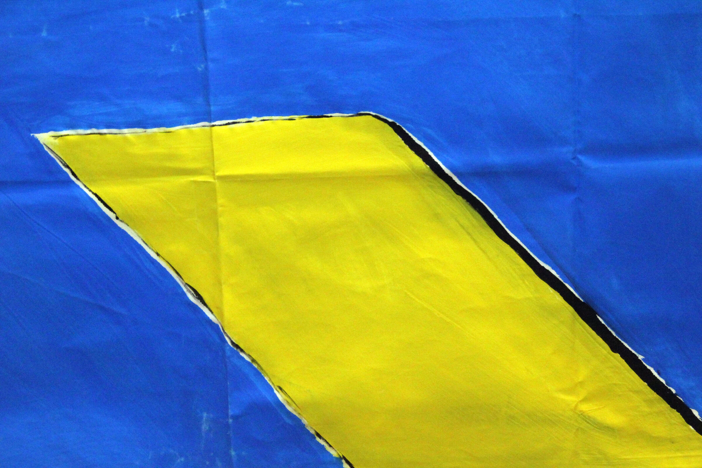 A detail of a diagonal yellow strip outlined in black on blue canvas.