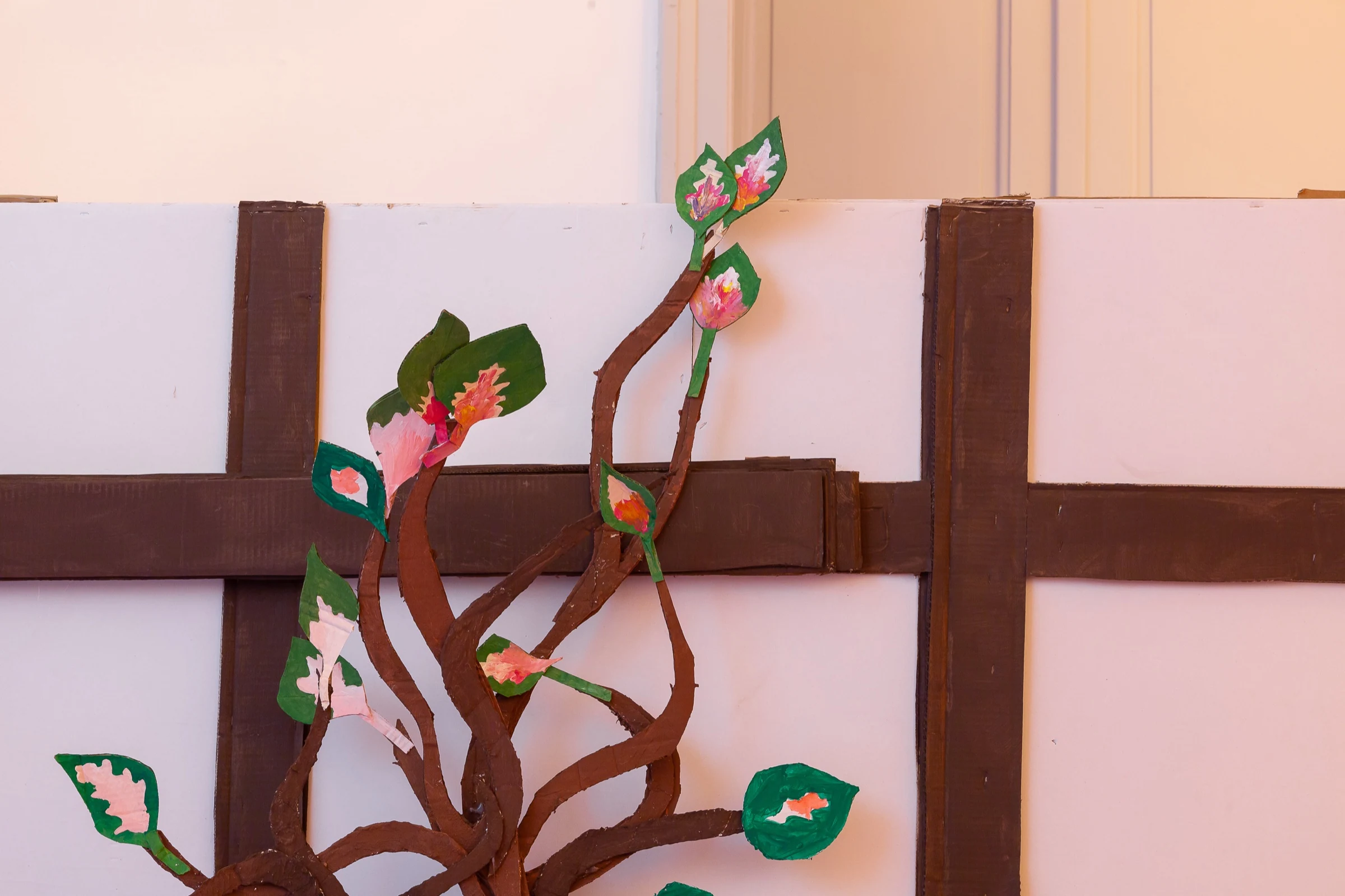 A handmade cardboard plant against the painted timber-frame wall.