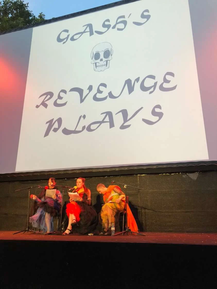 Three performers beneath a projection of the Gash’s Revenge Plays title.