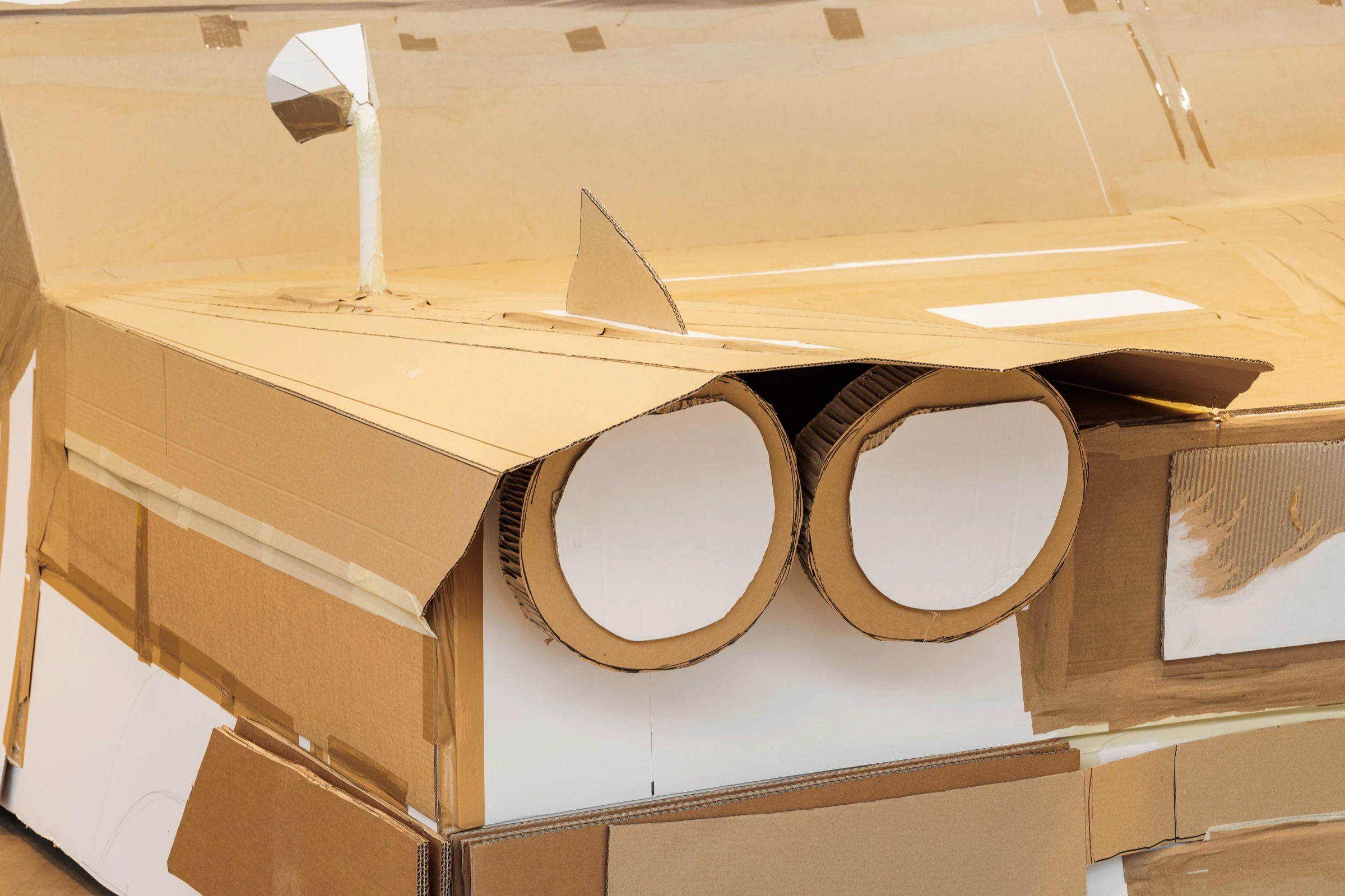 A close-up of handmade cardboard headlights, bonnet and wing mirror.