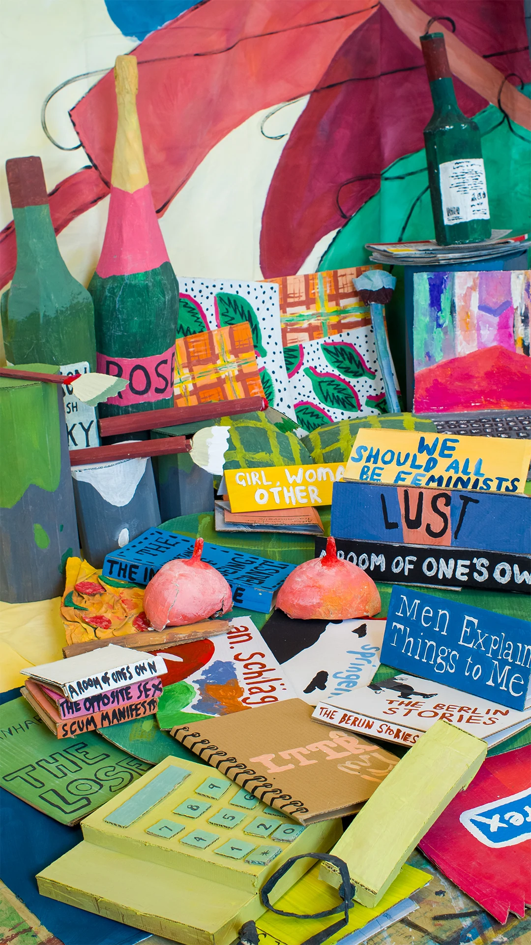 A pile of brightly coloured feminist and queer books arranged inside the Bedroom installation.