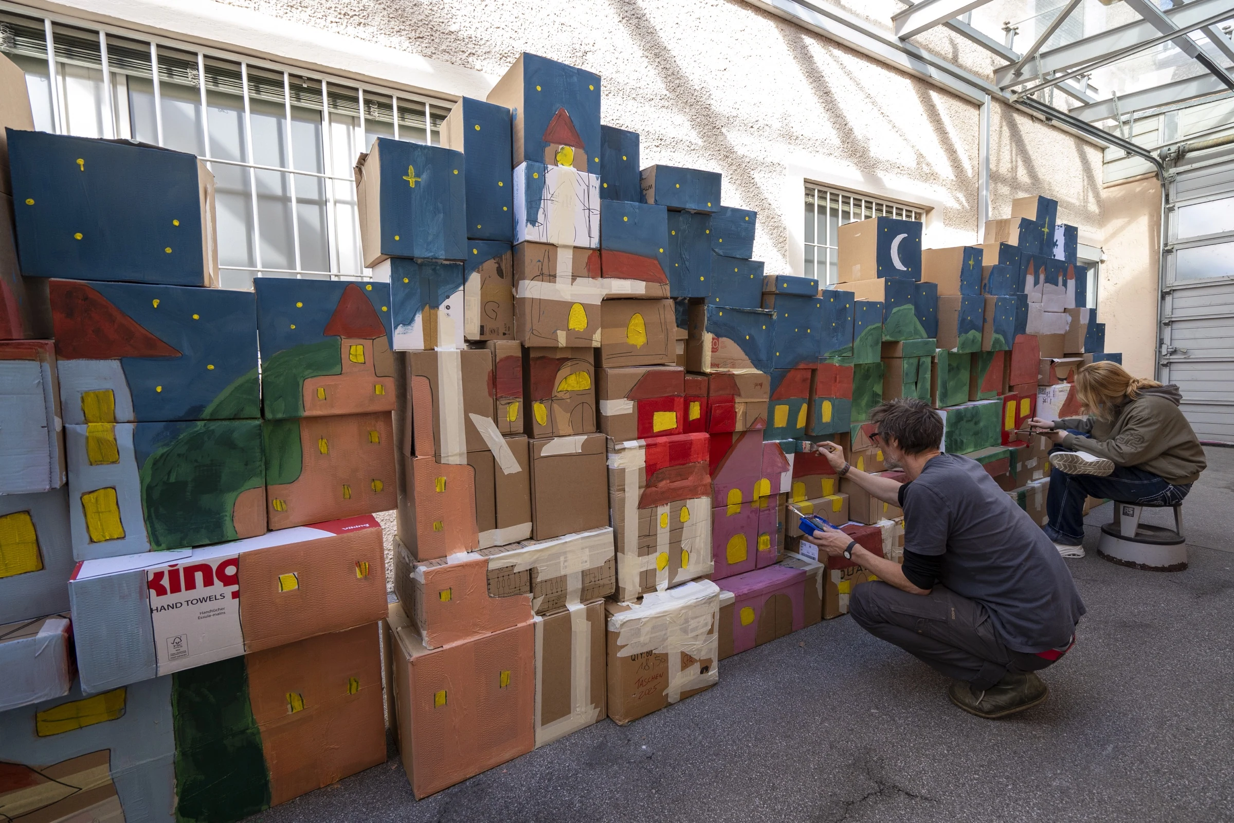Participants working on the painted cardboard castle wall.