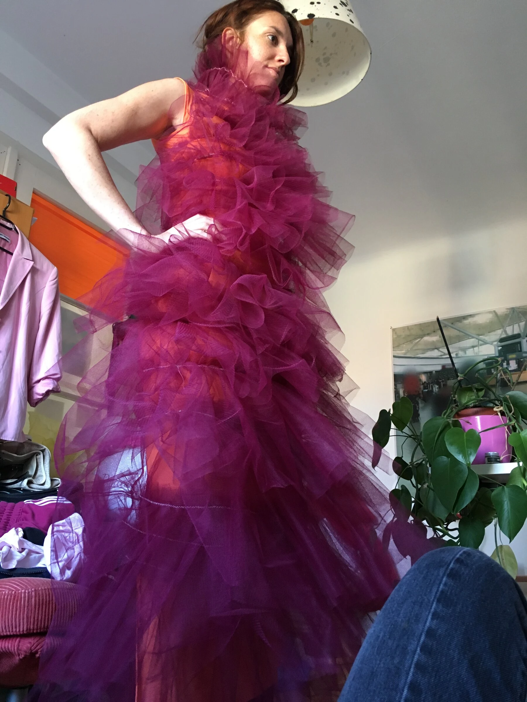 A performer modelling a magenta ruffled tulle dress indoors.