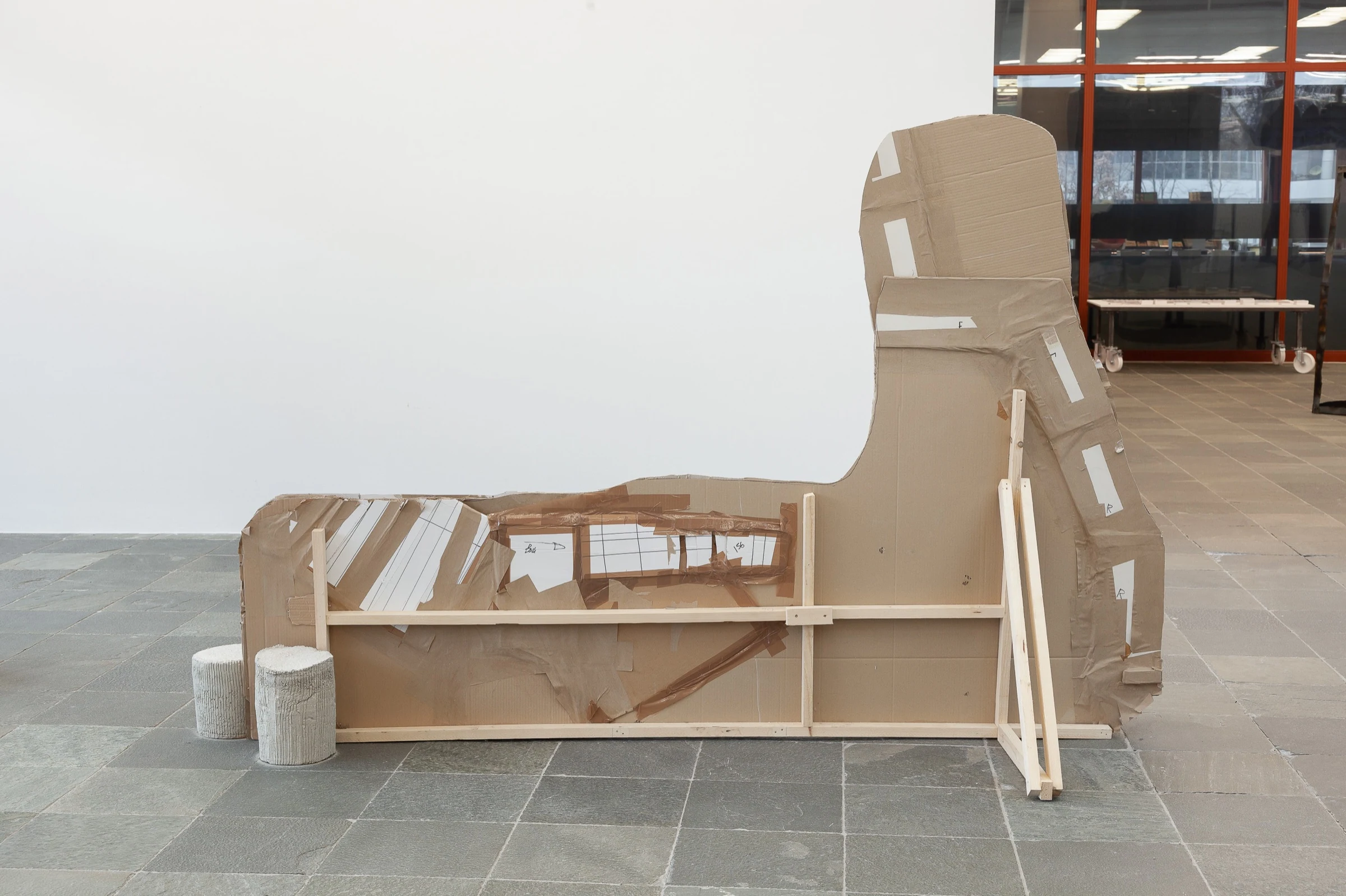 The rear of a cardboard sculpture showing its wooden supports and taped construction.