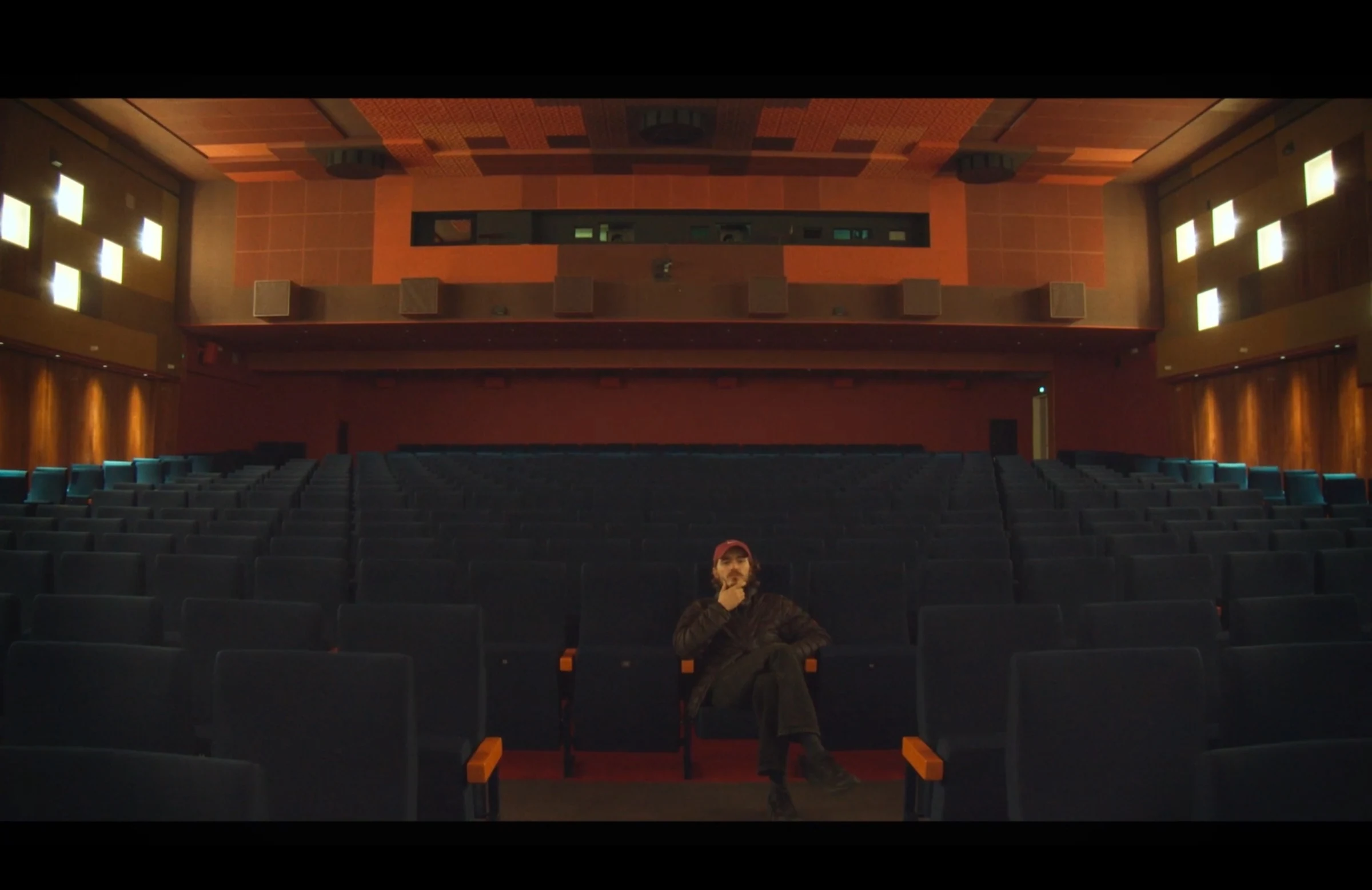A character sitting alone in a cinema auditorium.
