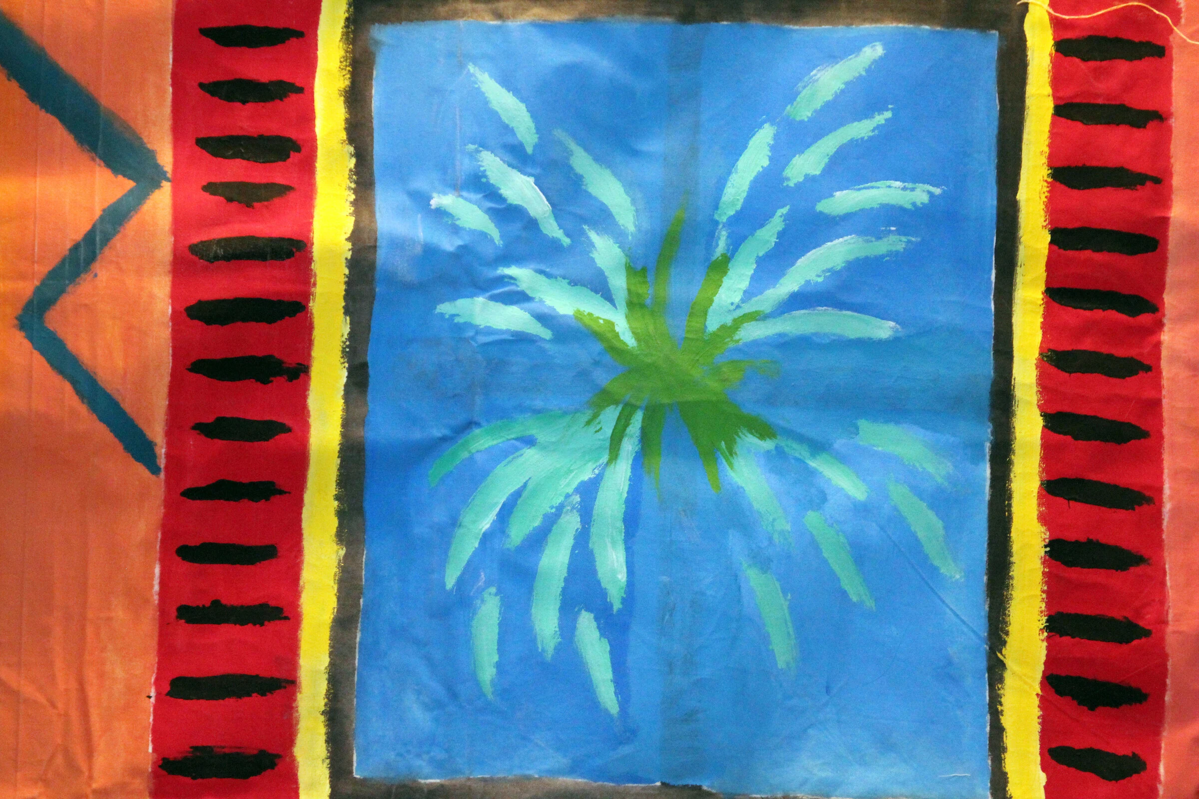 A detail of a green plant in a blue window framed by red shutters on the painted interior backdrop.