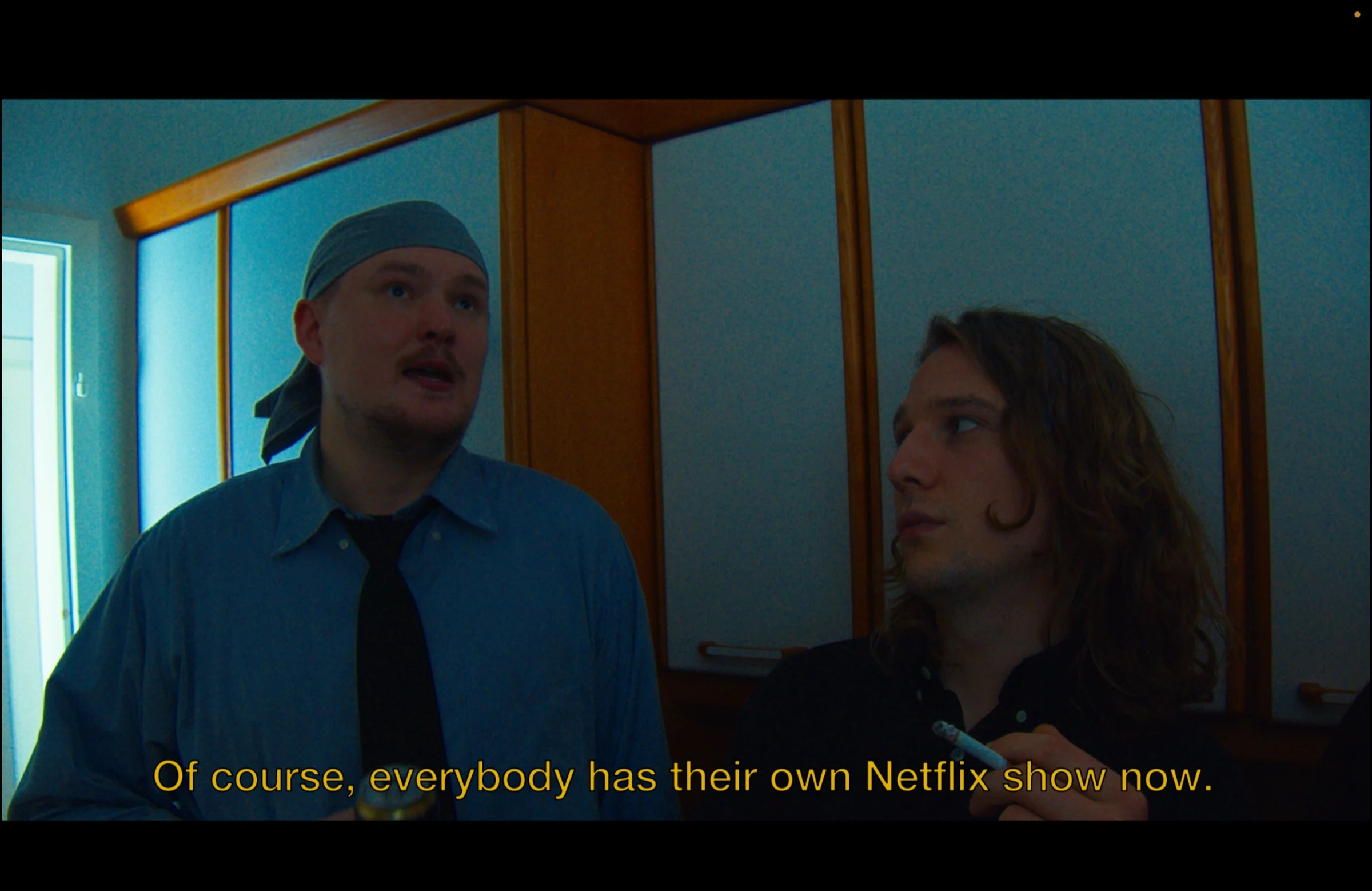 Two friends talking in a kitchen, subtitled Of course, everybody has their own Netflix show now.