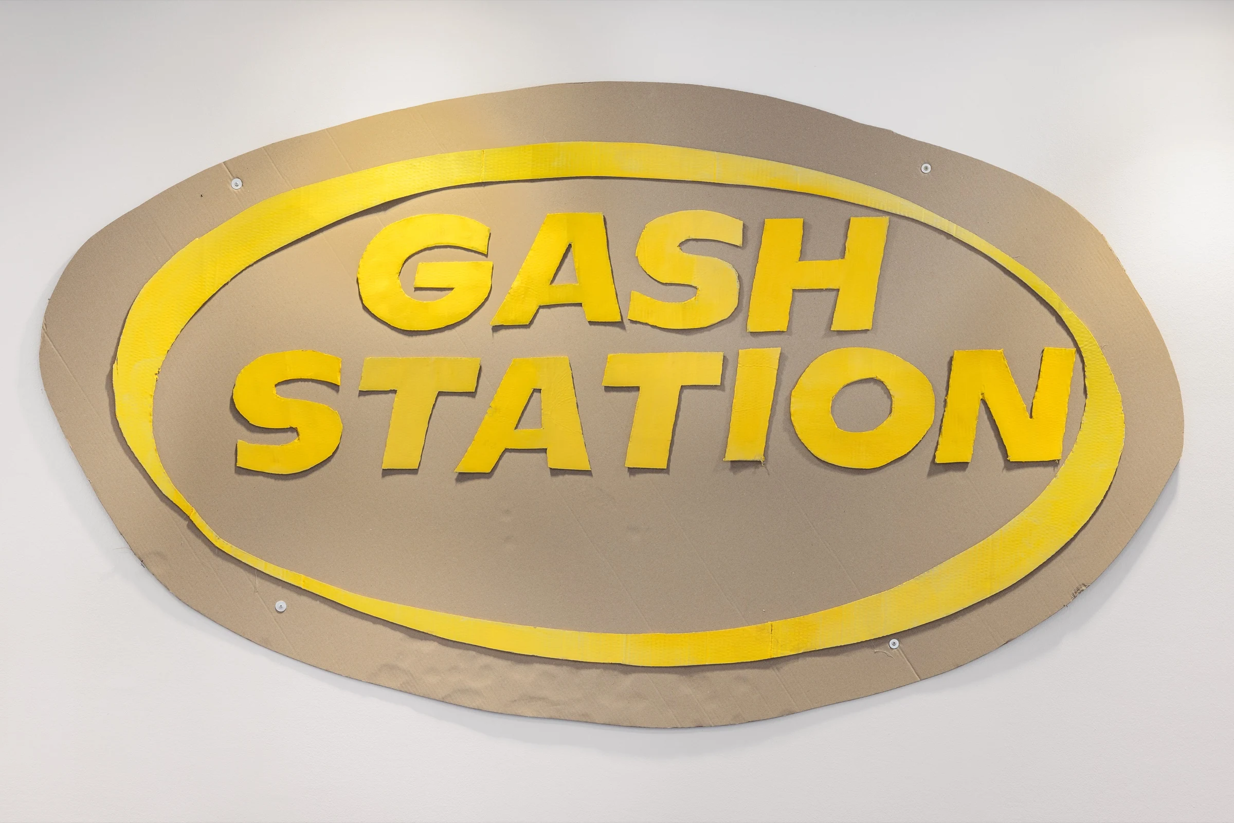 An oval cardboard GASH STATION sign with raised yellow lettering.