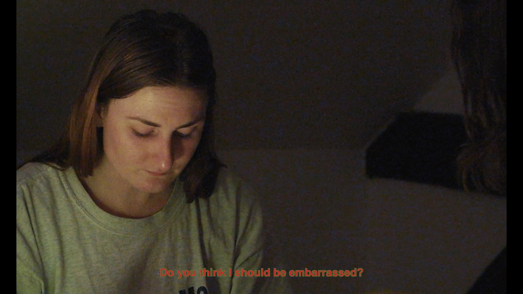 A woman looking down in a dimly lit room.
