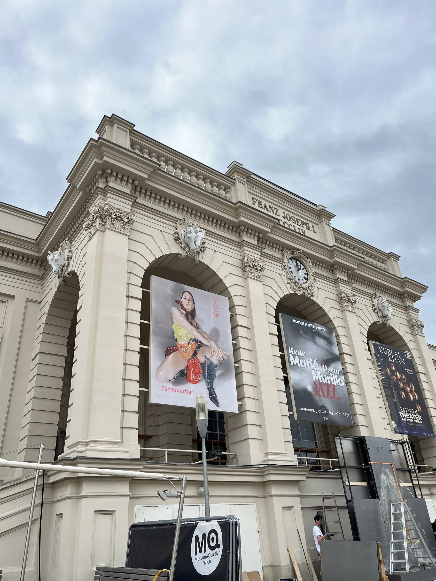 An angled view of the Tanzquartier building with the large portrait poster above its entrance.