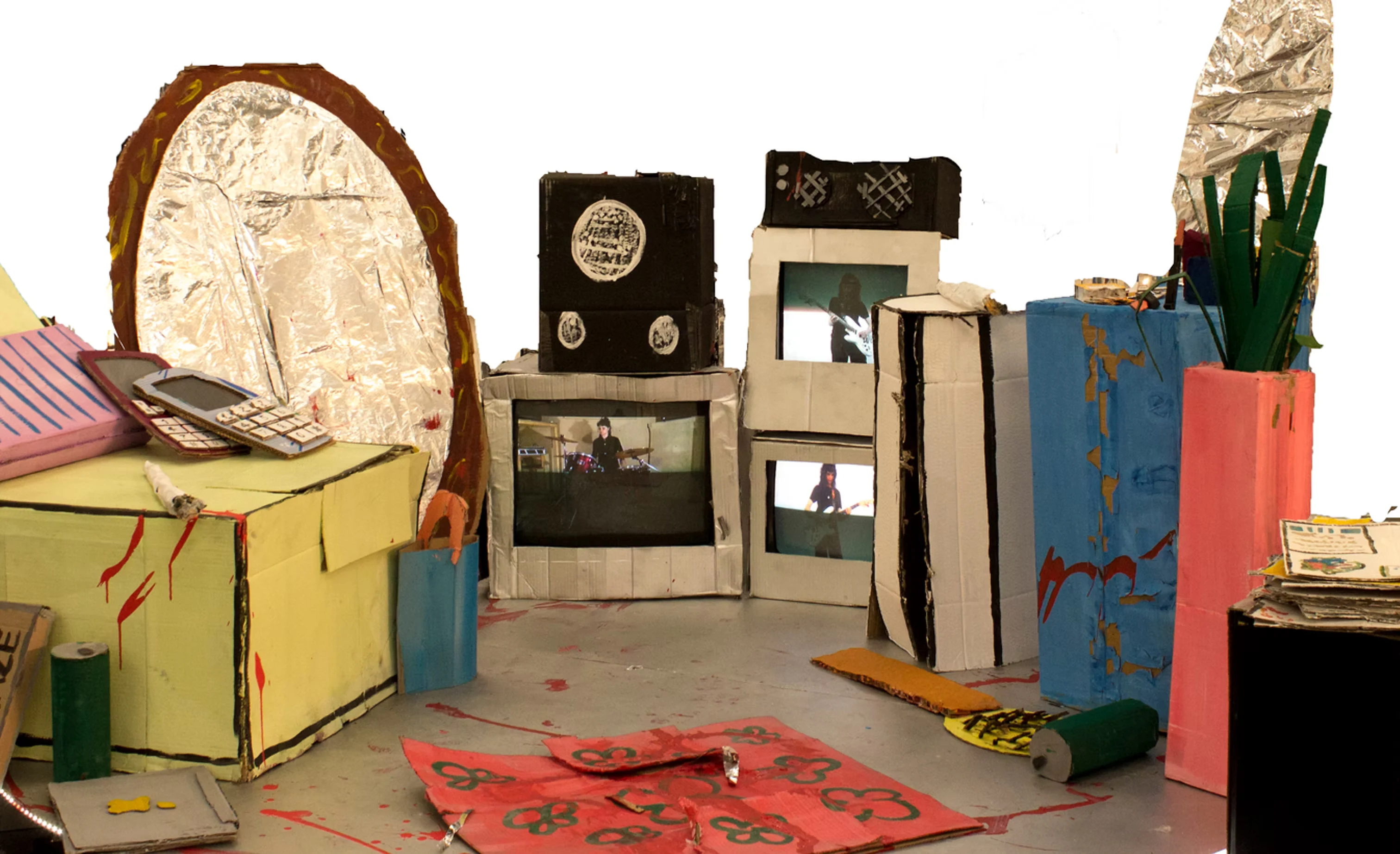A handmade cardboard room filled with painted furniture, screens, props and silver foil sculptures