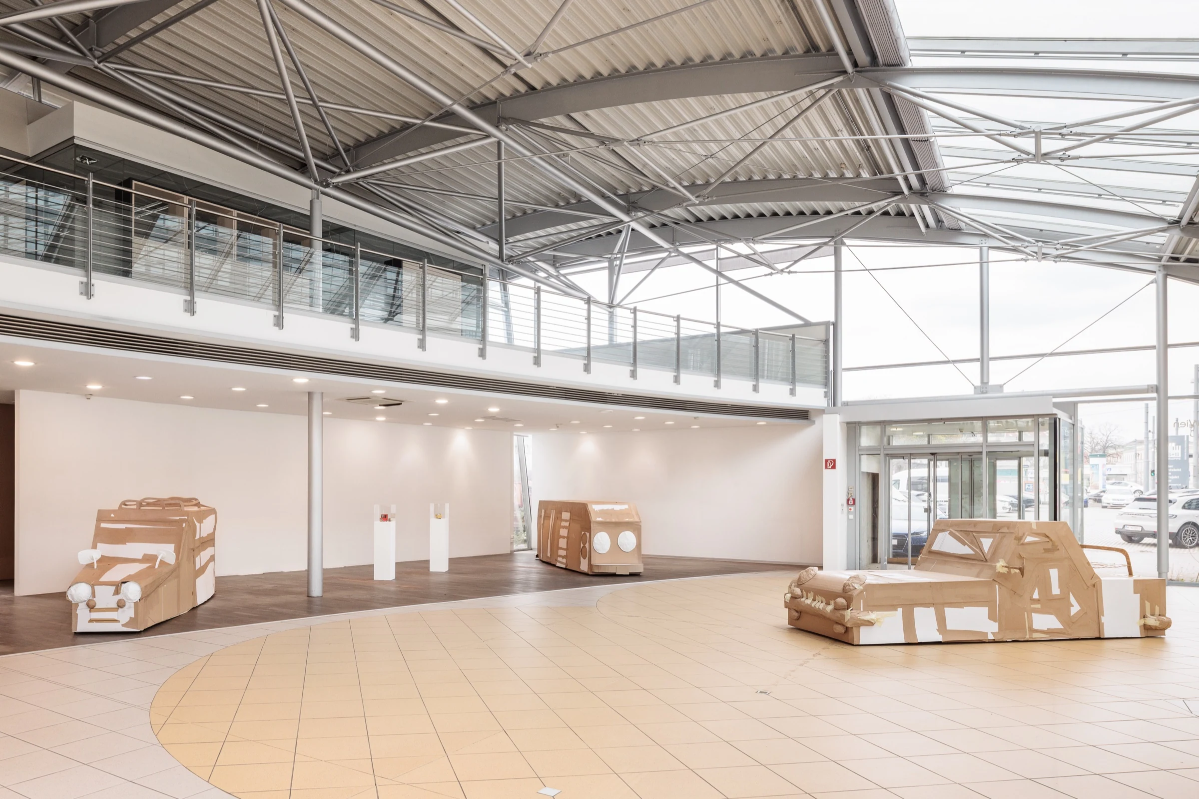 Cardboard vehicle sculptures arranged around the showroom entrance.