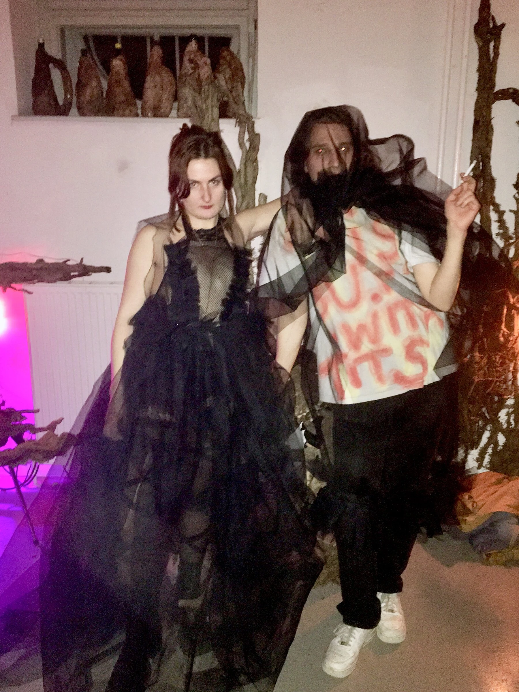 Two people wearing black tulle costumes at a gathering.