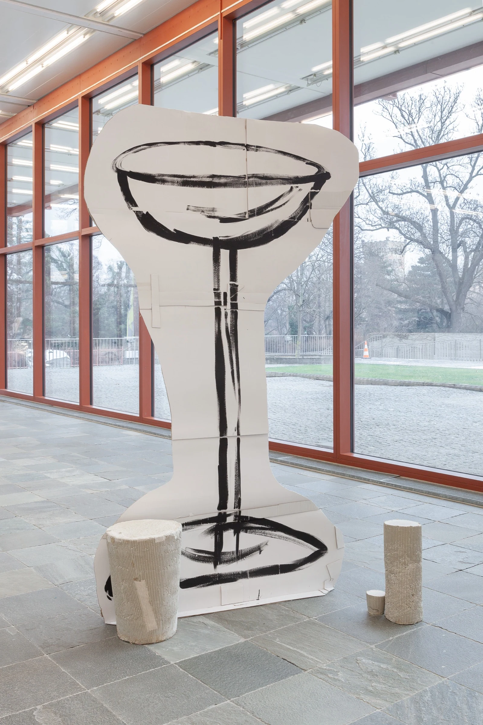 An oversized cardboard cocktail glass beside the orange-framed gallery windows.