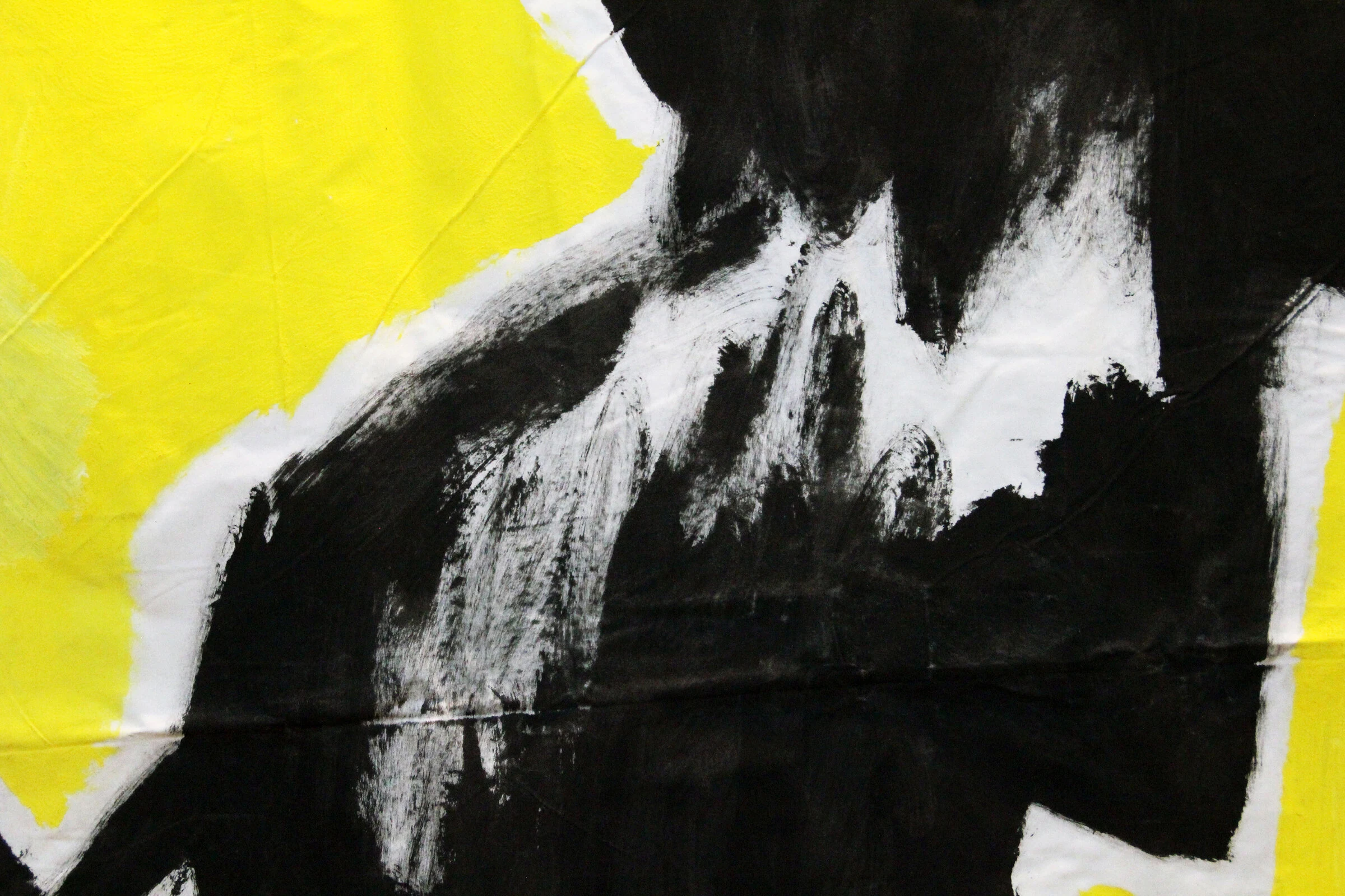 A close-up of black brushstrokes and a yellow star outlined in white on canvas.