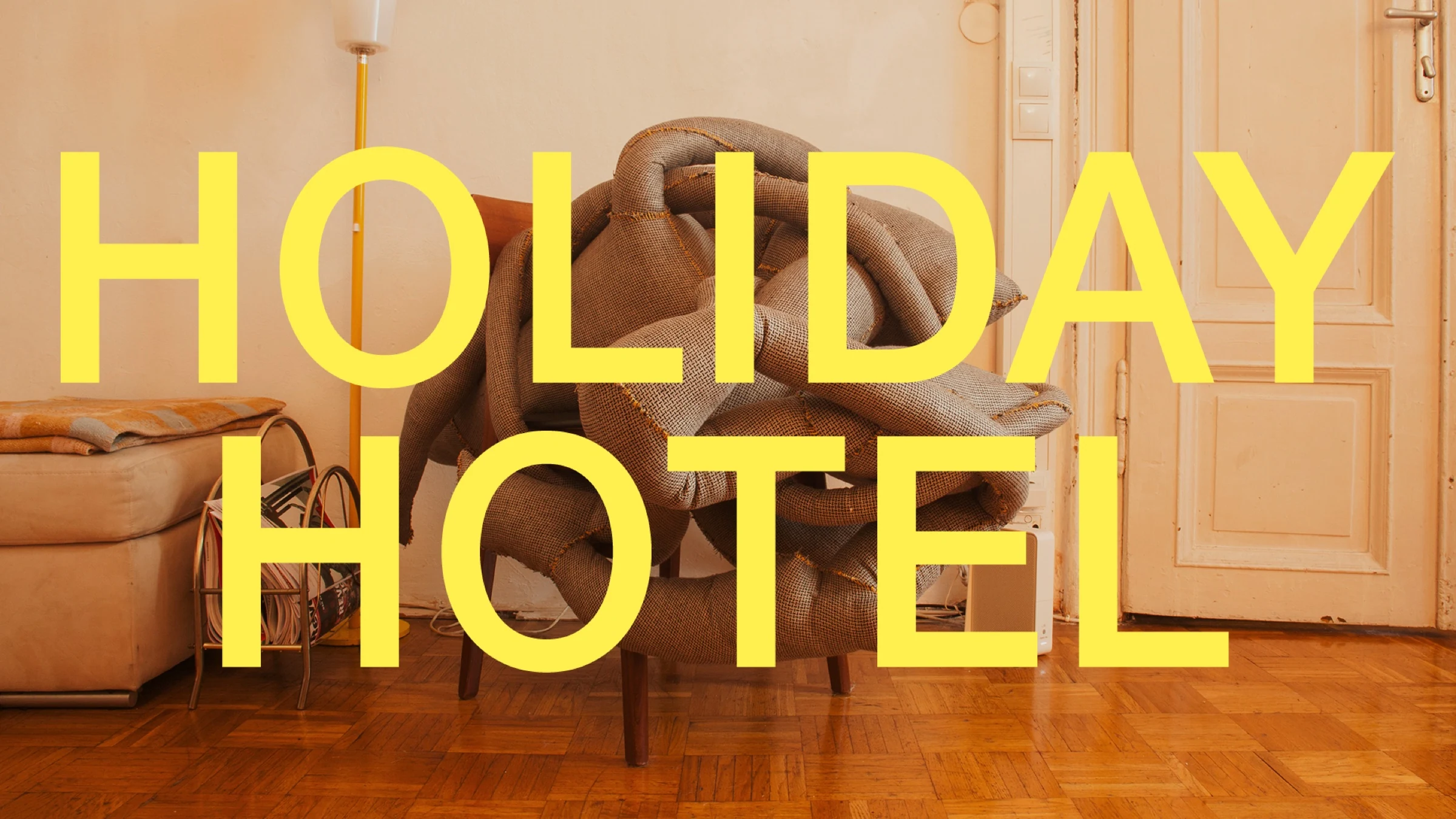 Holiday Hotel title page with yellow lettering over a chair piled with fabric.