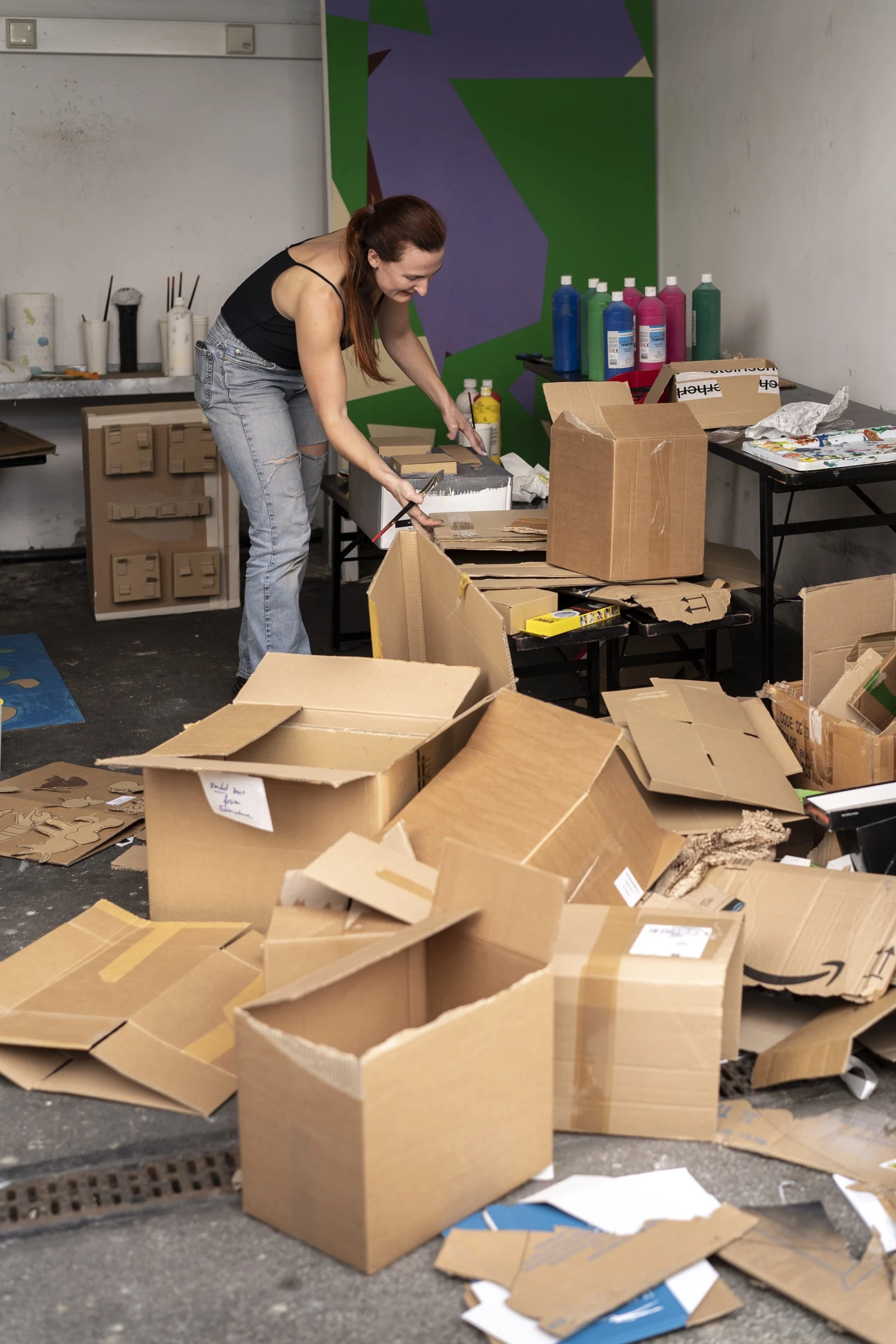 Charlotte Gash sorting cardboard boxes and workshop materials.