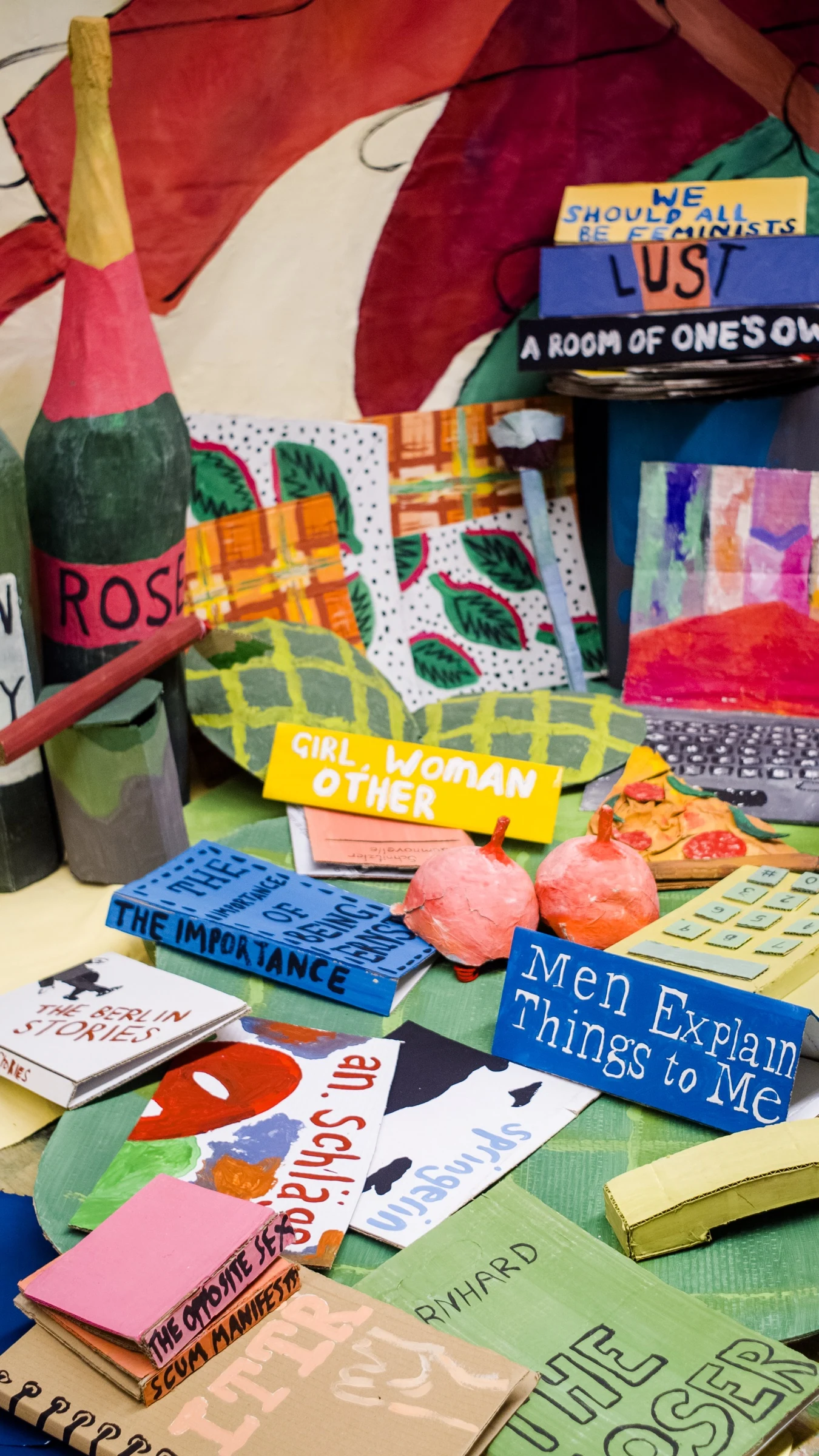 A portrait view of BEDROOM with colourful cardboard books, bottles, a laptop and a yellow telephone.