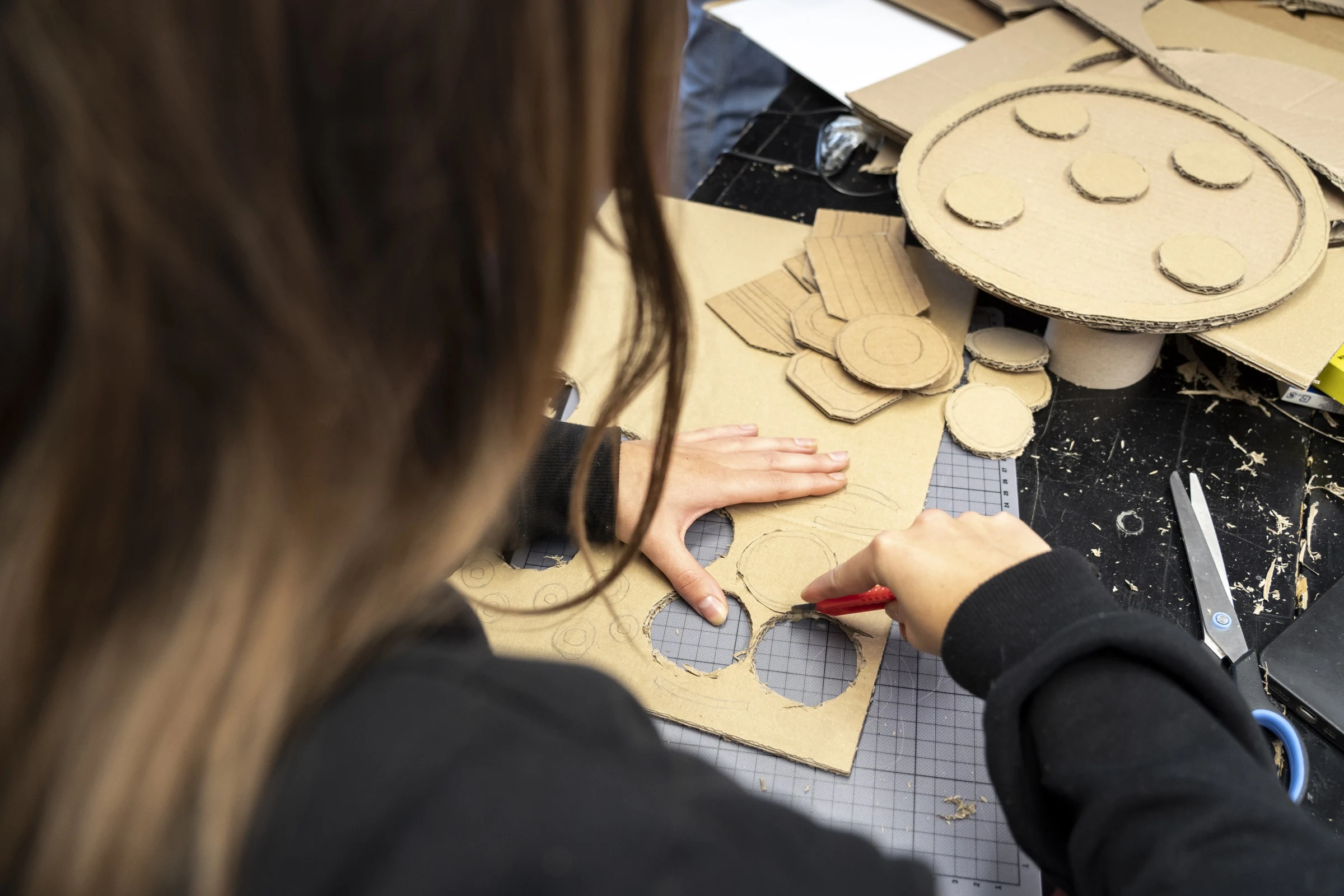 A participant cutting circles from cardboard with a utility knife.