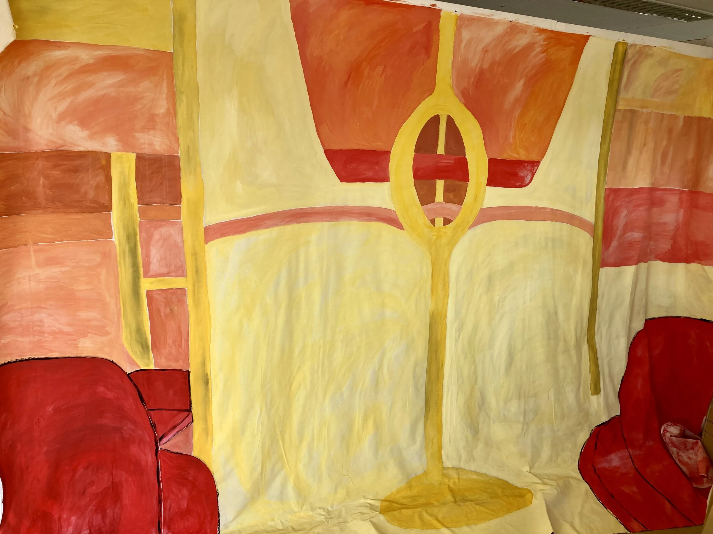 A yellow and orange painted interior backdrop with red chairs and a floor lamp.