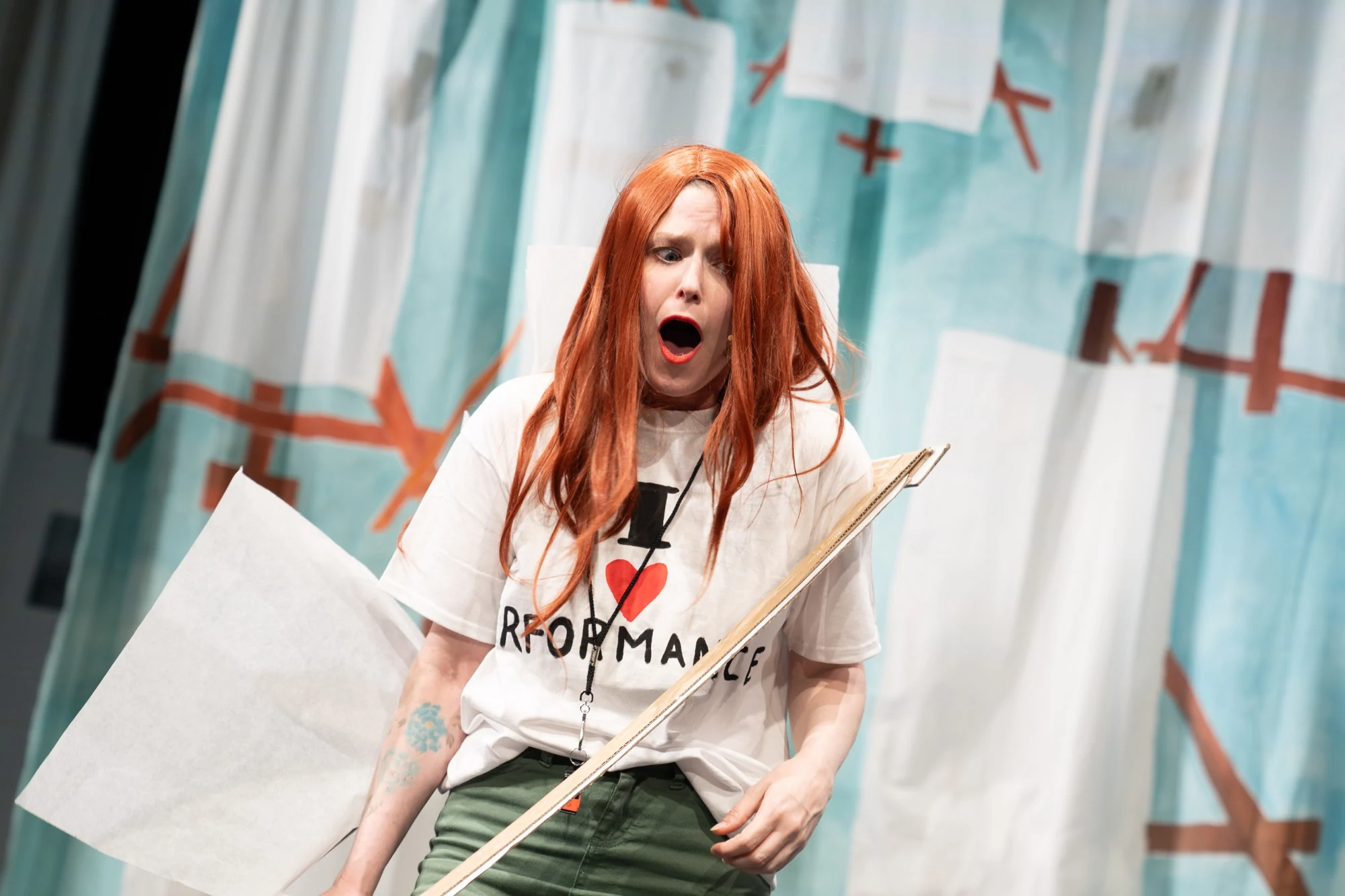 Charlotte performing with a script in front of the painted studio backdrop.