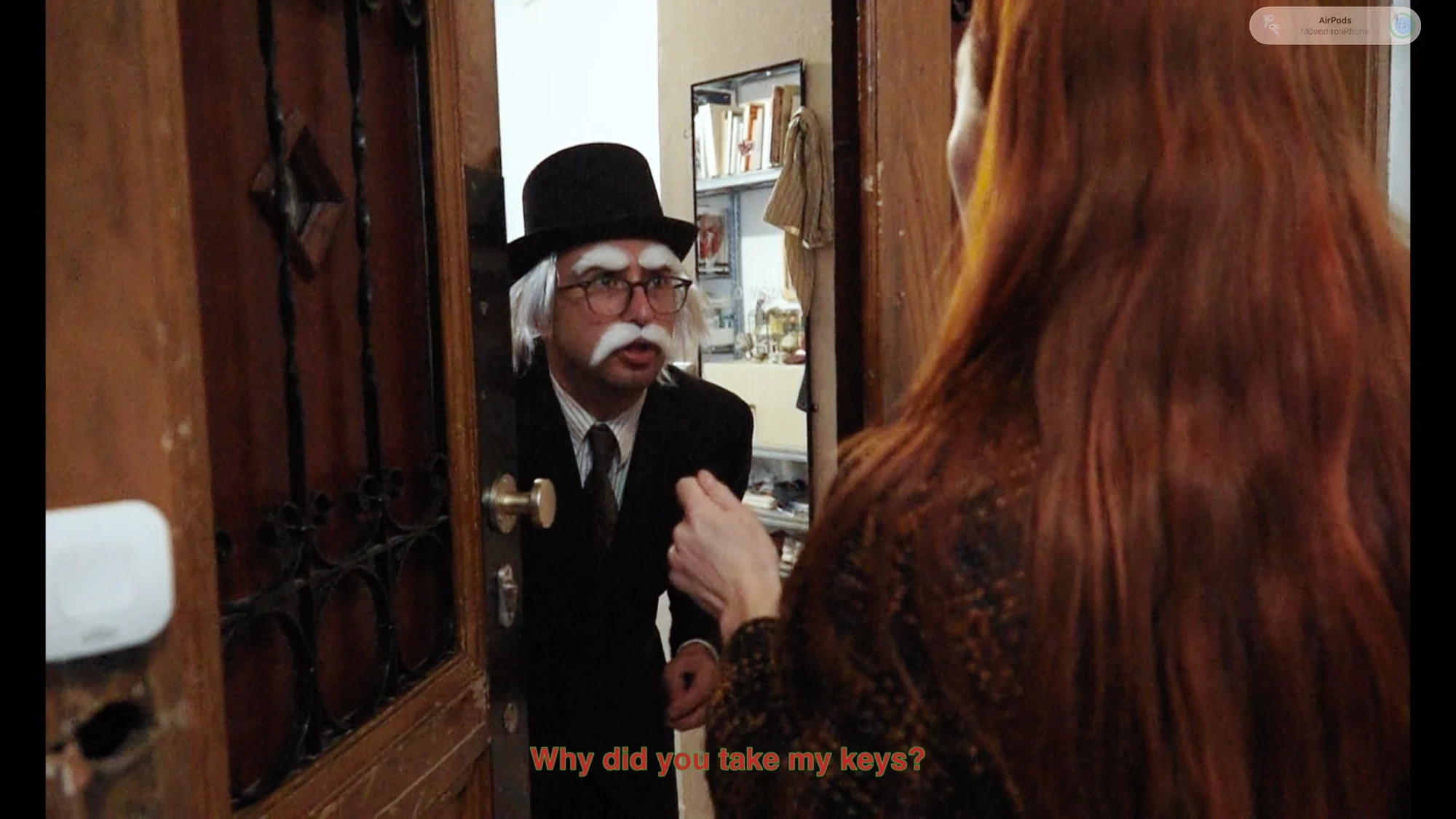 Charlotte talking at a doorway to a character in a top hat with white eyebrows and a moustache.