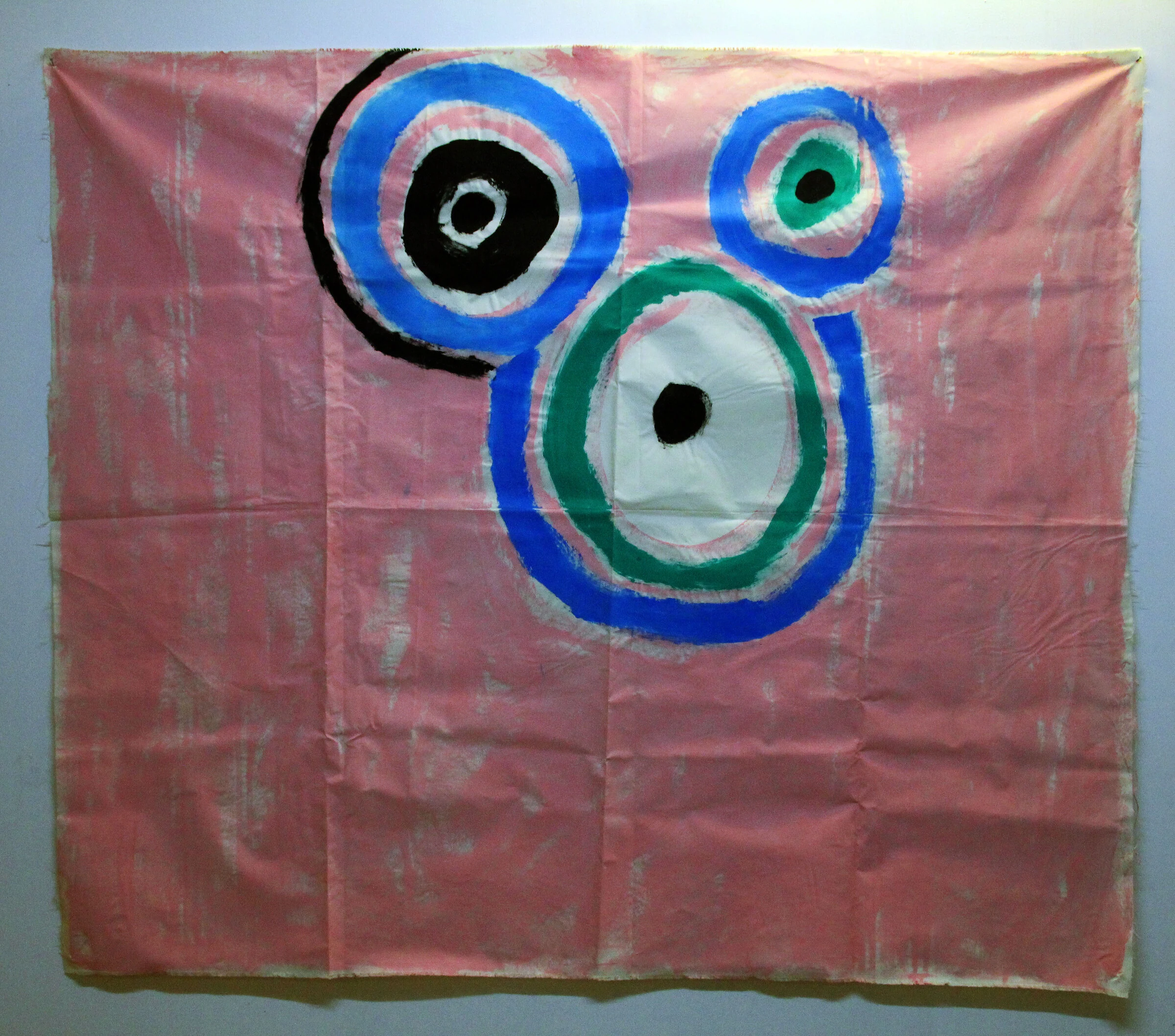 A pink canvas backdrop with three large circular shapes in blue, green, black and white.
