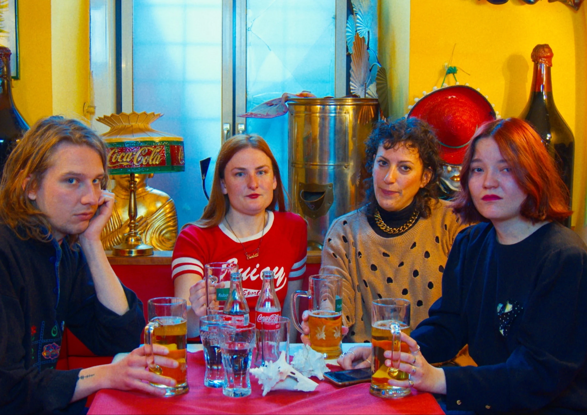 Four friends with glasses of beer in a colourful bar.