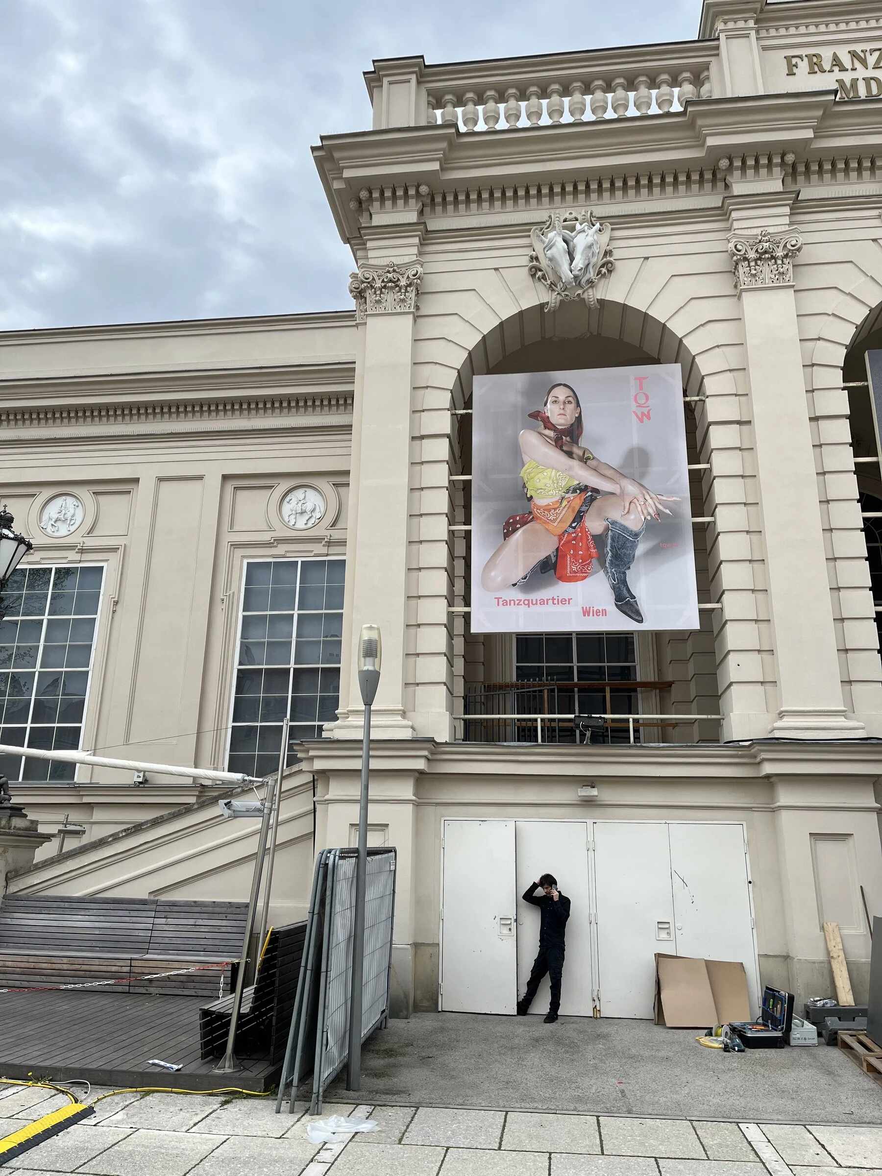 The bandana and denim boots poster displayed above an entrance on the Tanzquartier building.