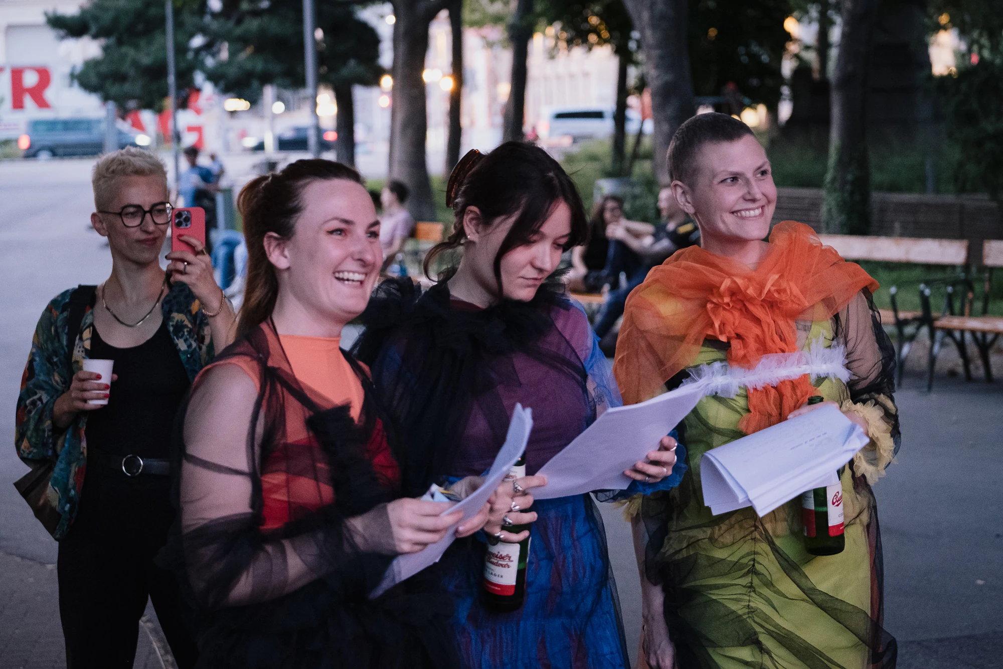 Three costumed performers holding scripts outdoors before a performance.