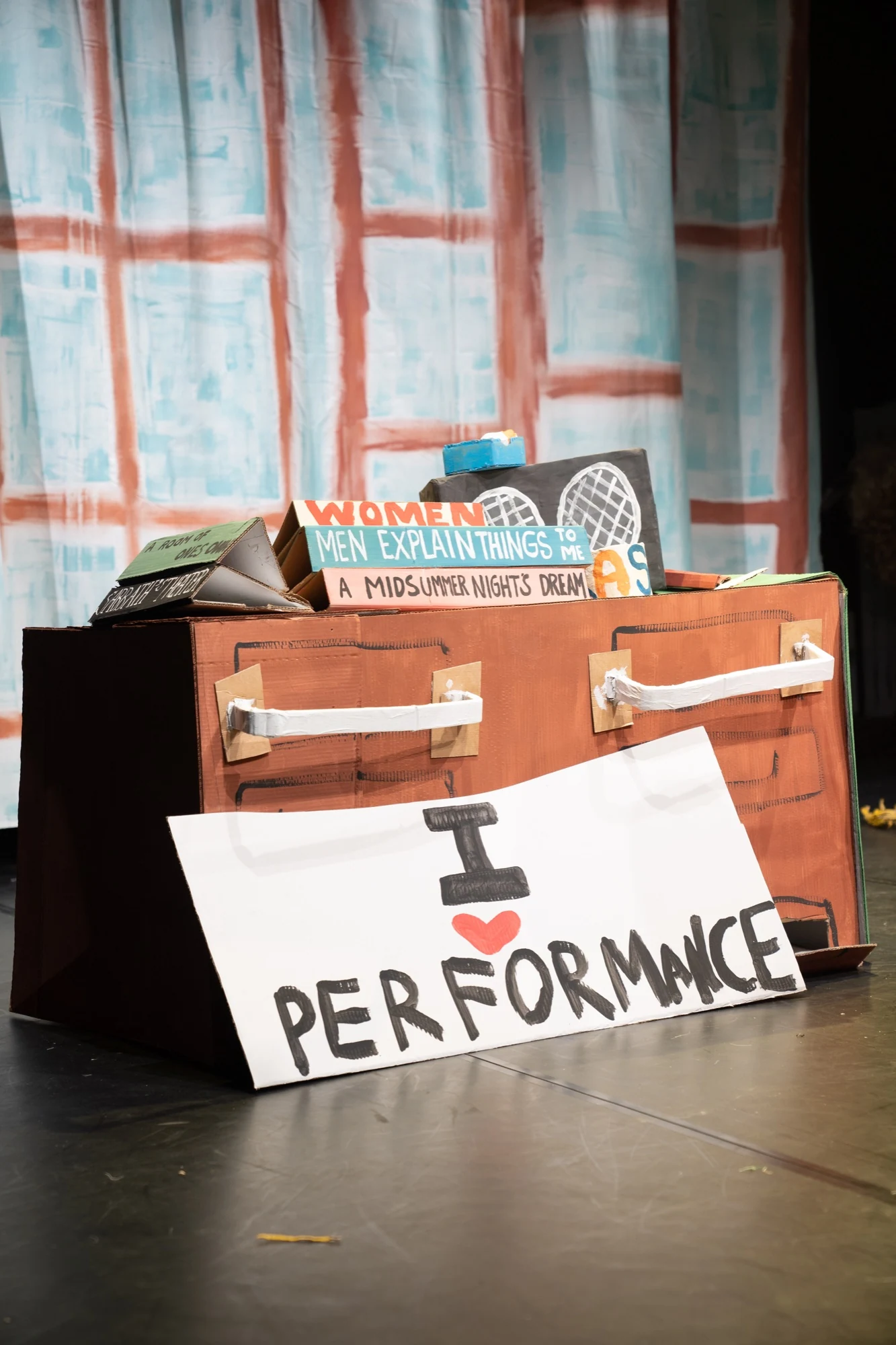 Handmade cardboard books, a cabinet and an I love performance sign.