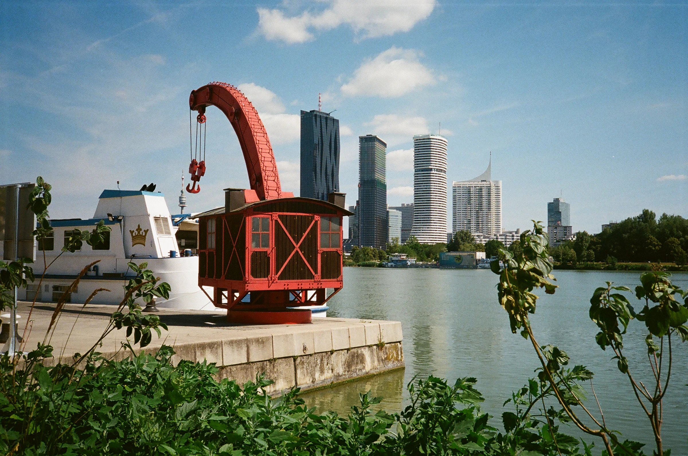 A red crane beside the river, with Vienna's skyline in the background.