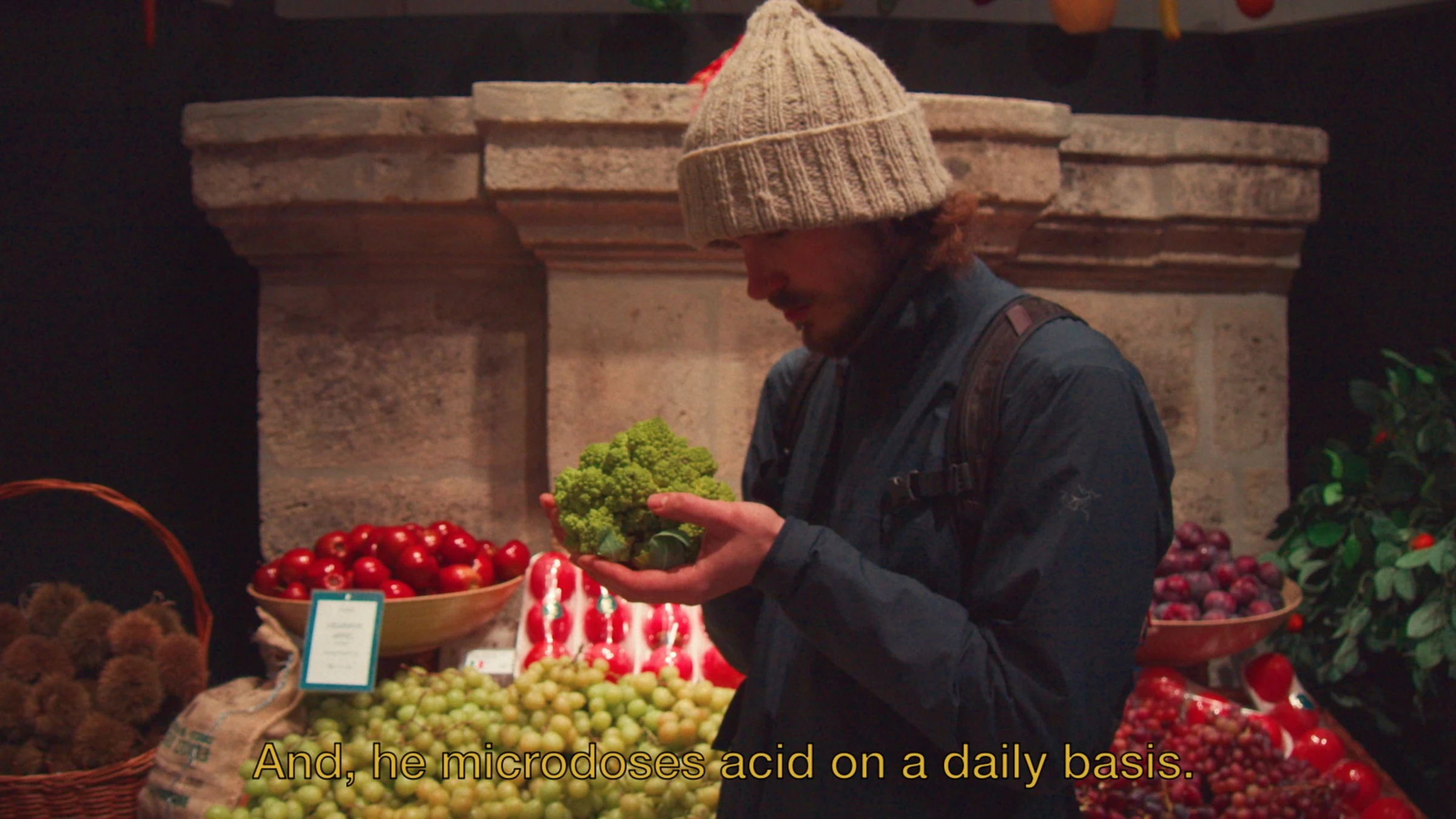 Young Man holding a romanesco in a produce shop.