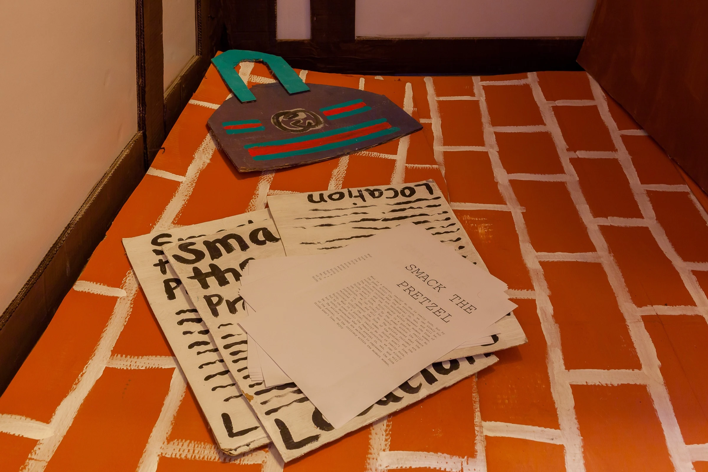 Printed publications and a handmade cardboard object on the painted floor.