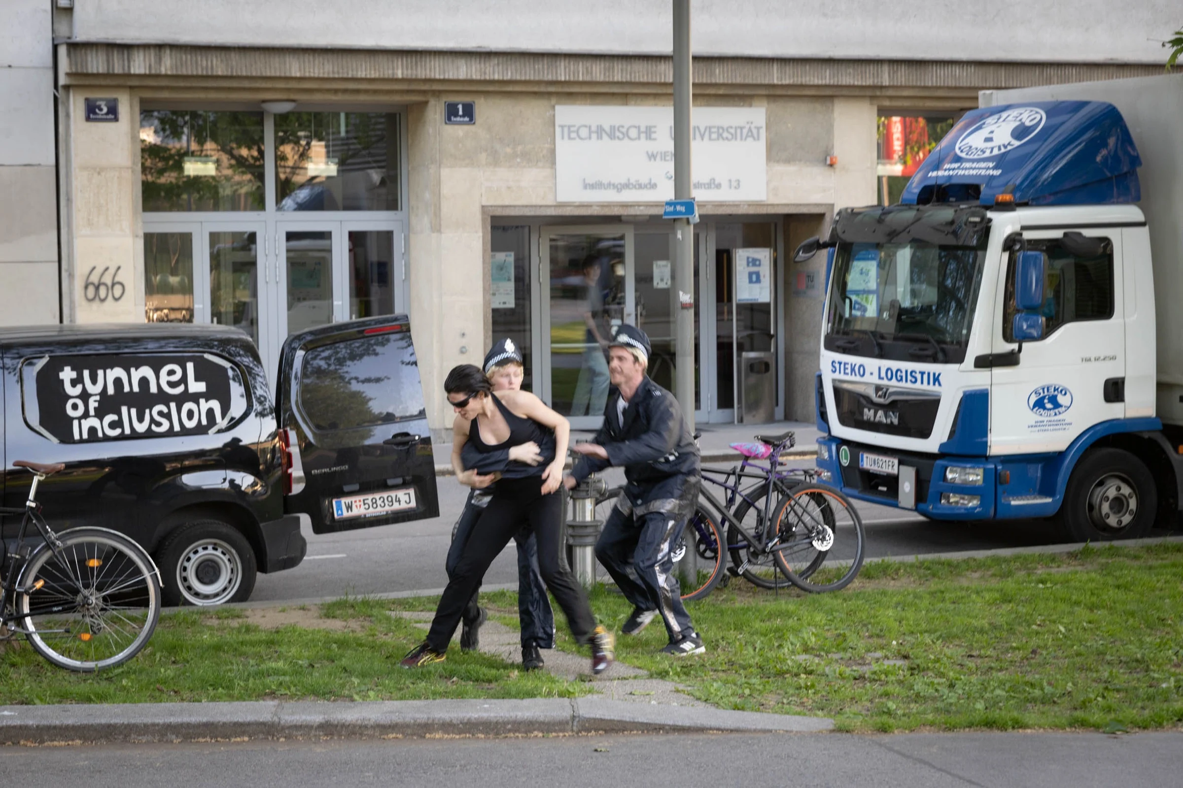 An outdoor performance beside a Tunnel of Inclusion van, with performers in police costumes.
