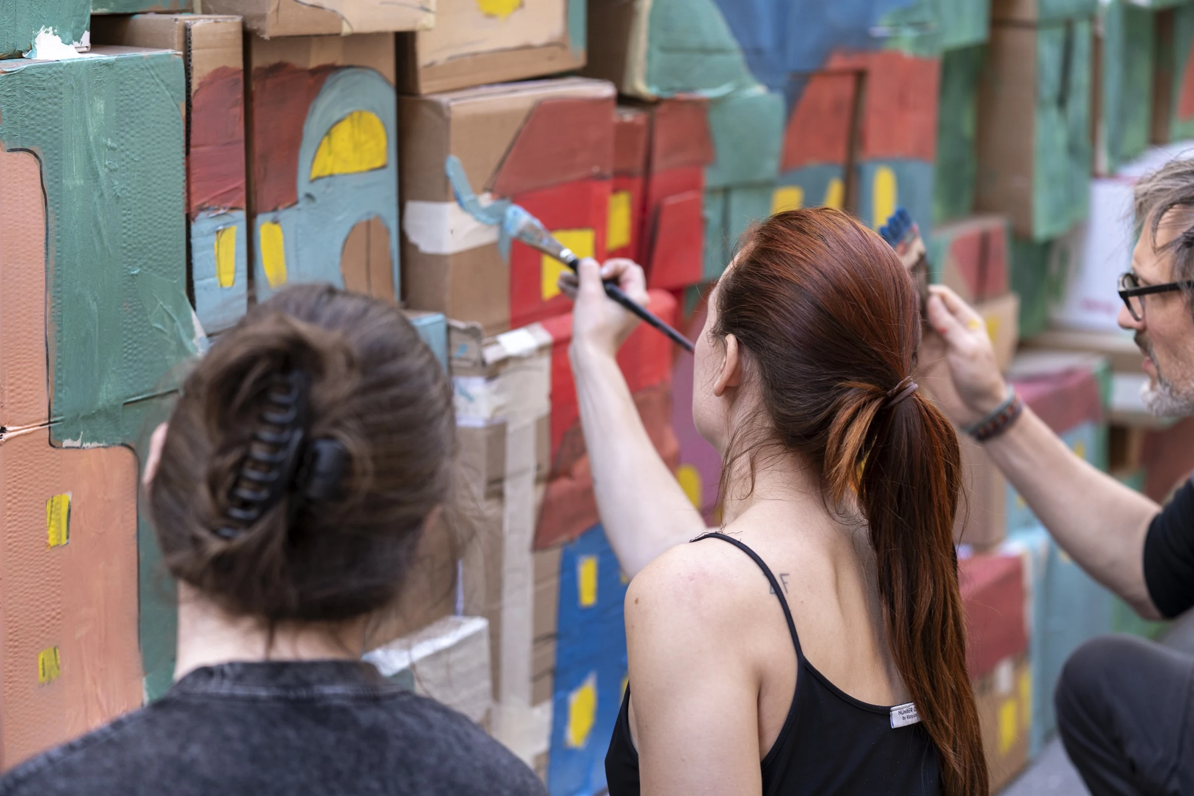 Participants painting turquoise details on the cardboard castle wall.
