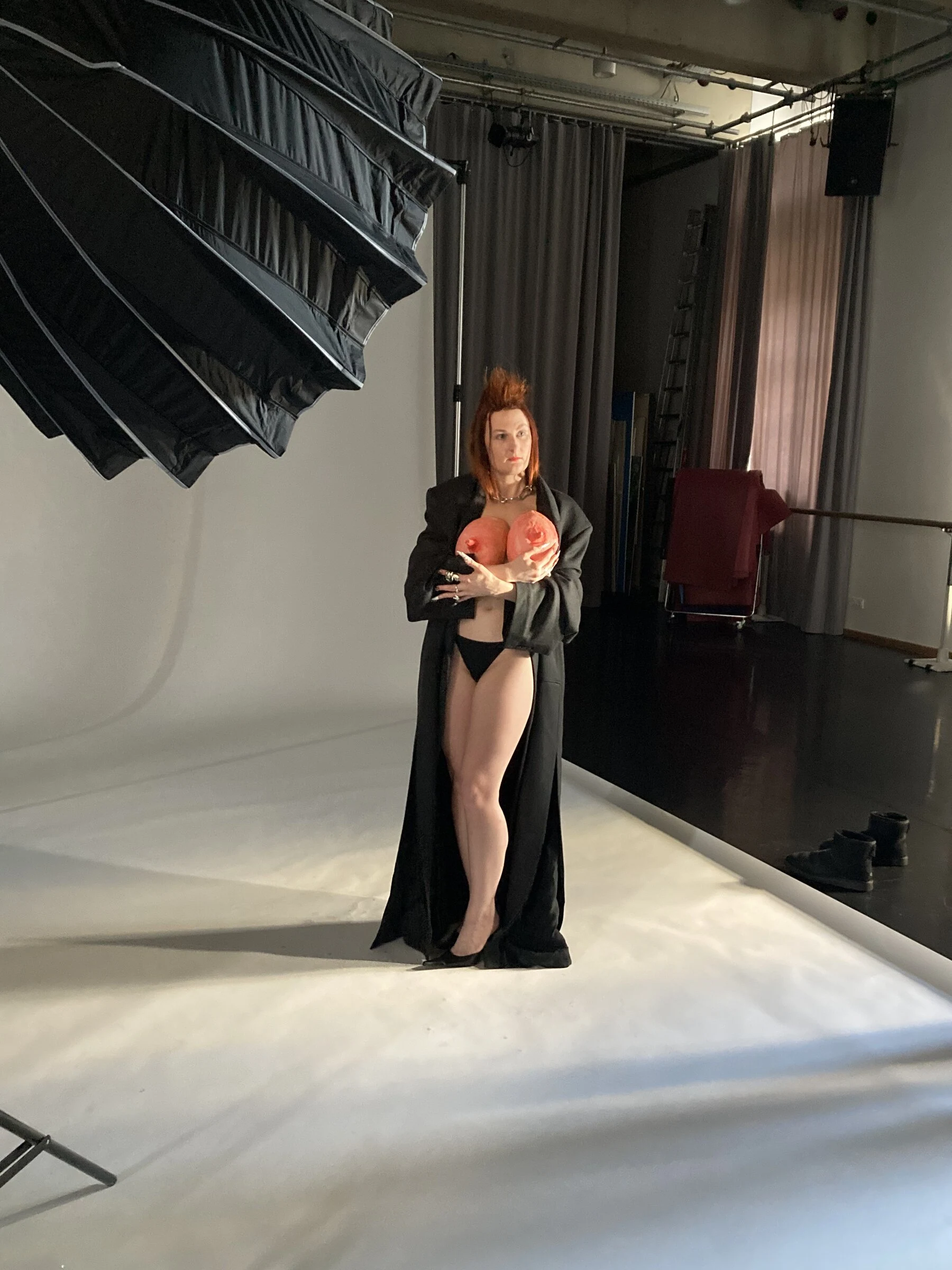 Charlotte posing in a long black outfit on a white studio backdrop.